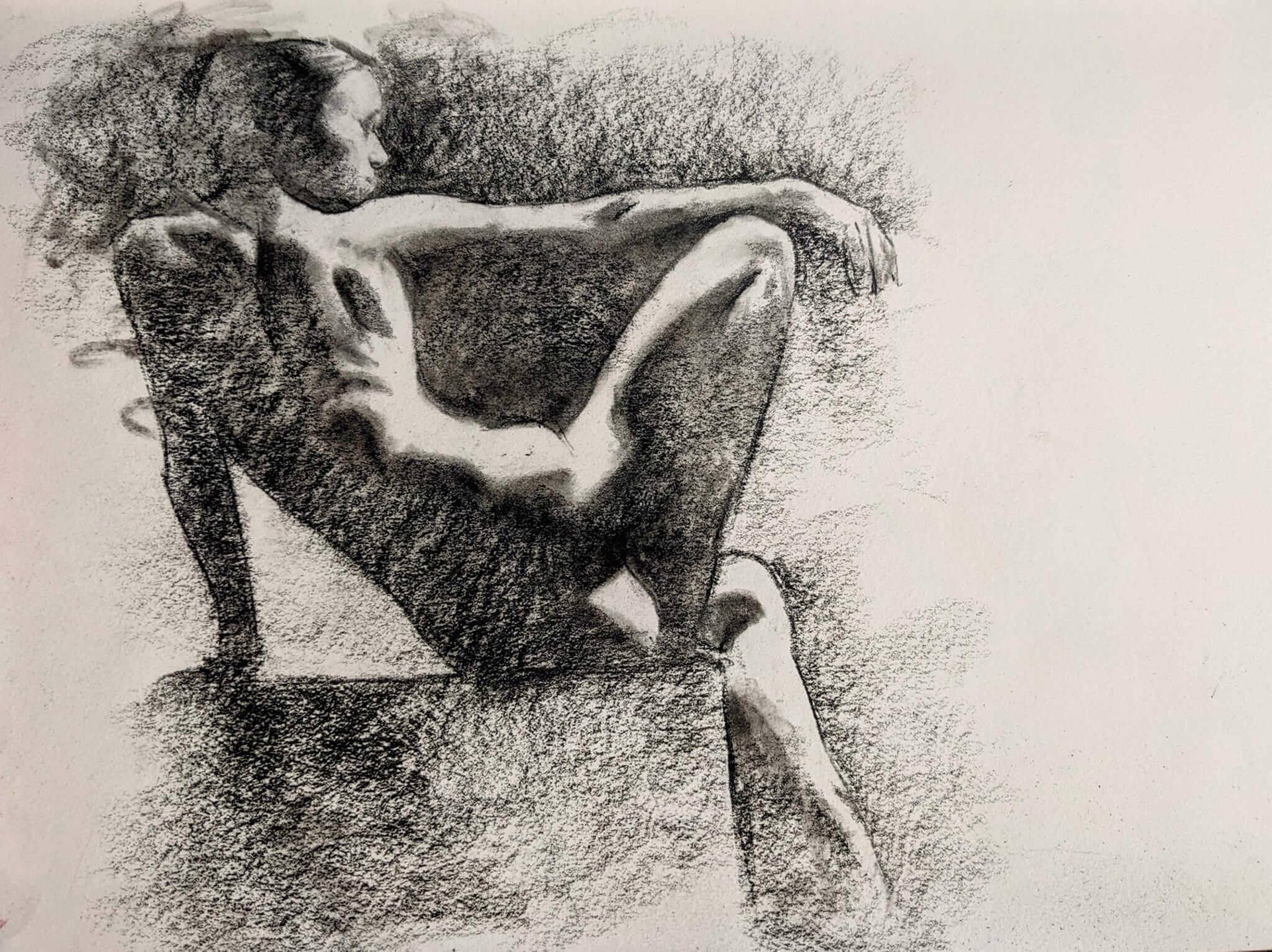 A charcoal study of a nude figure seated in profile, emphasizing form and shadow.