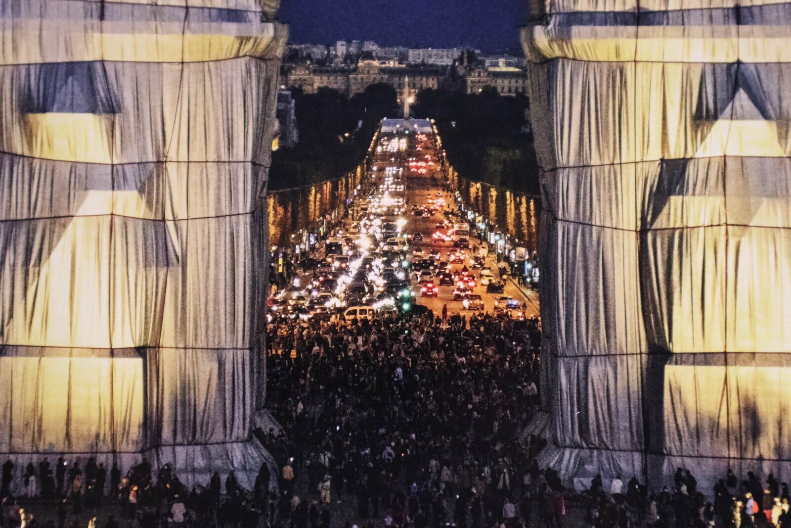 A massive archway draped in flowing fabric, illuminated against a dark night sky.