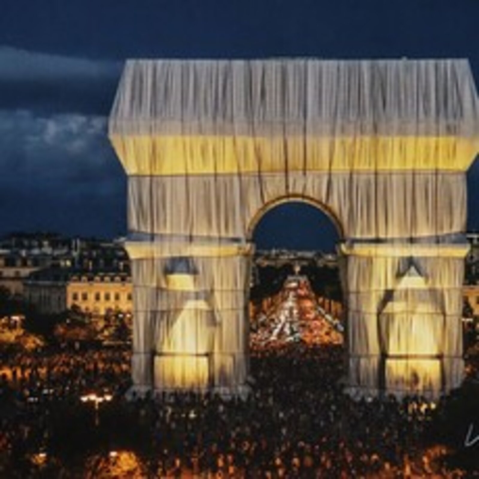 A massive archway draped in flowing fabric, illuminated against a dark night sky.