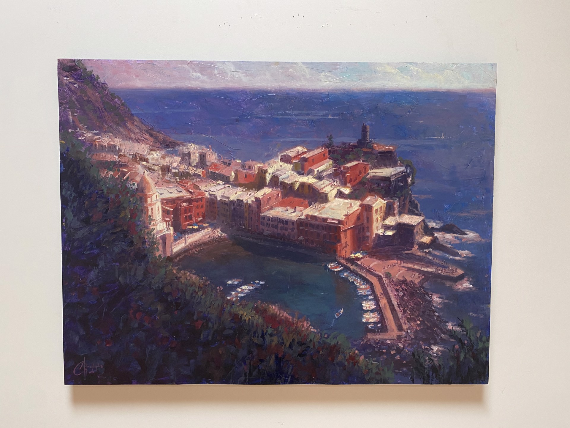 A coastal village nestled on a cliffside overlooking the sea, painted in warm ochre tones against deep blues.