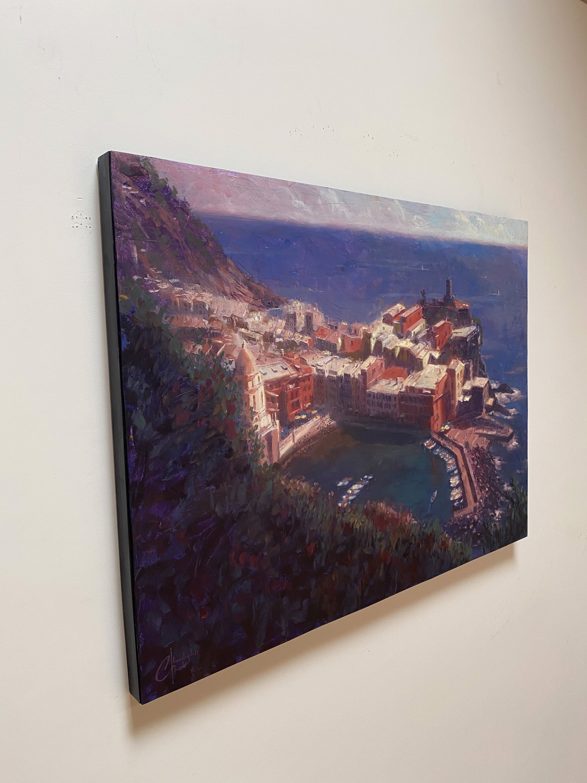 A coastal village nestled on a cliffside overlooking the sea, painted in warm ochre tones against deep blues.