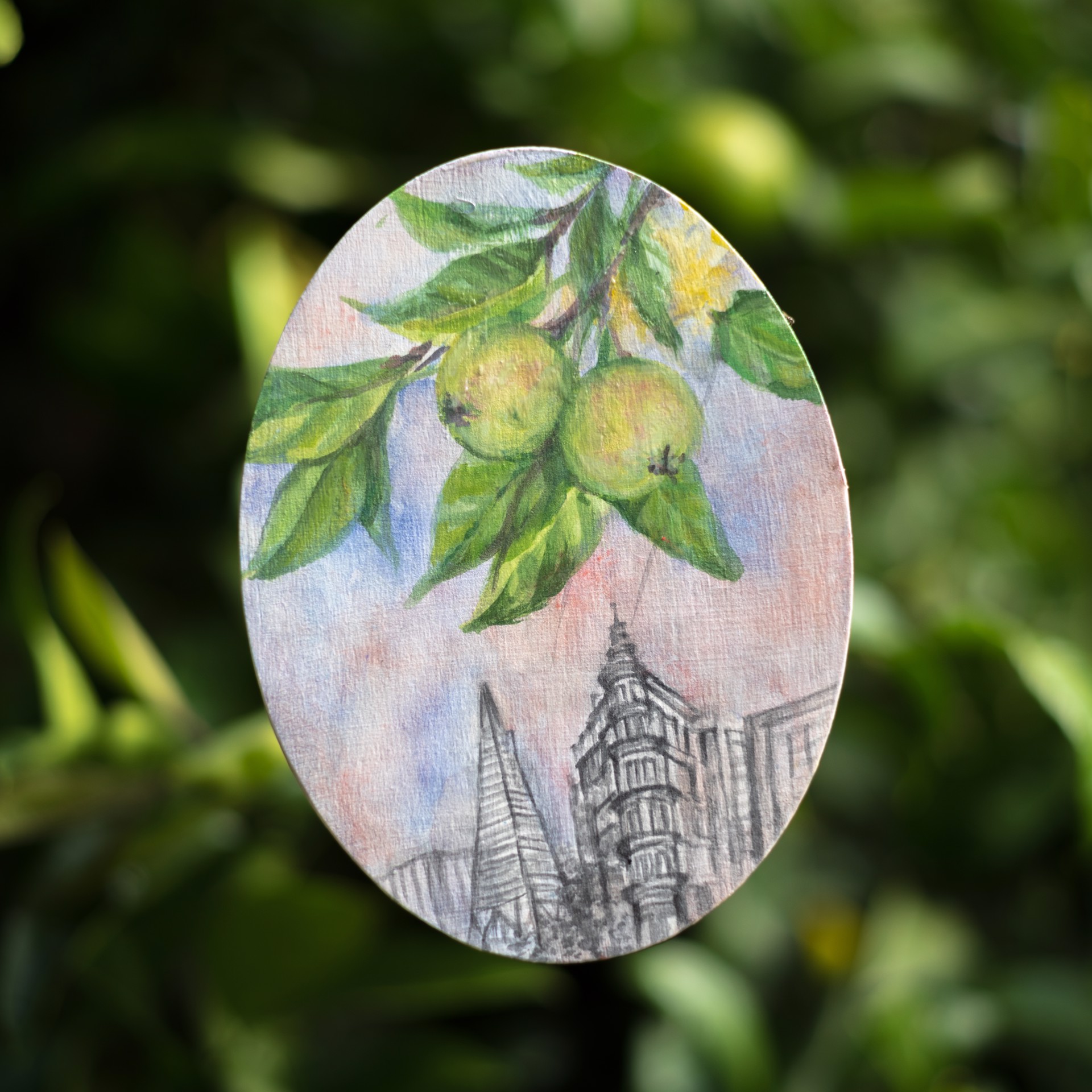 A layered oval artwork blending a fruit branch with a city skyline sketch against a soft background.