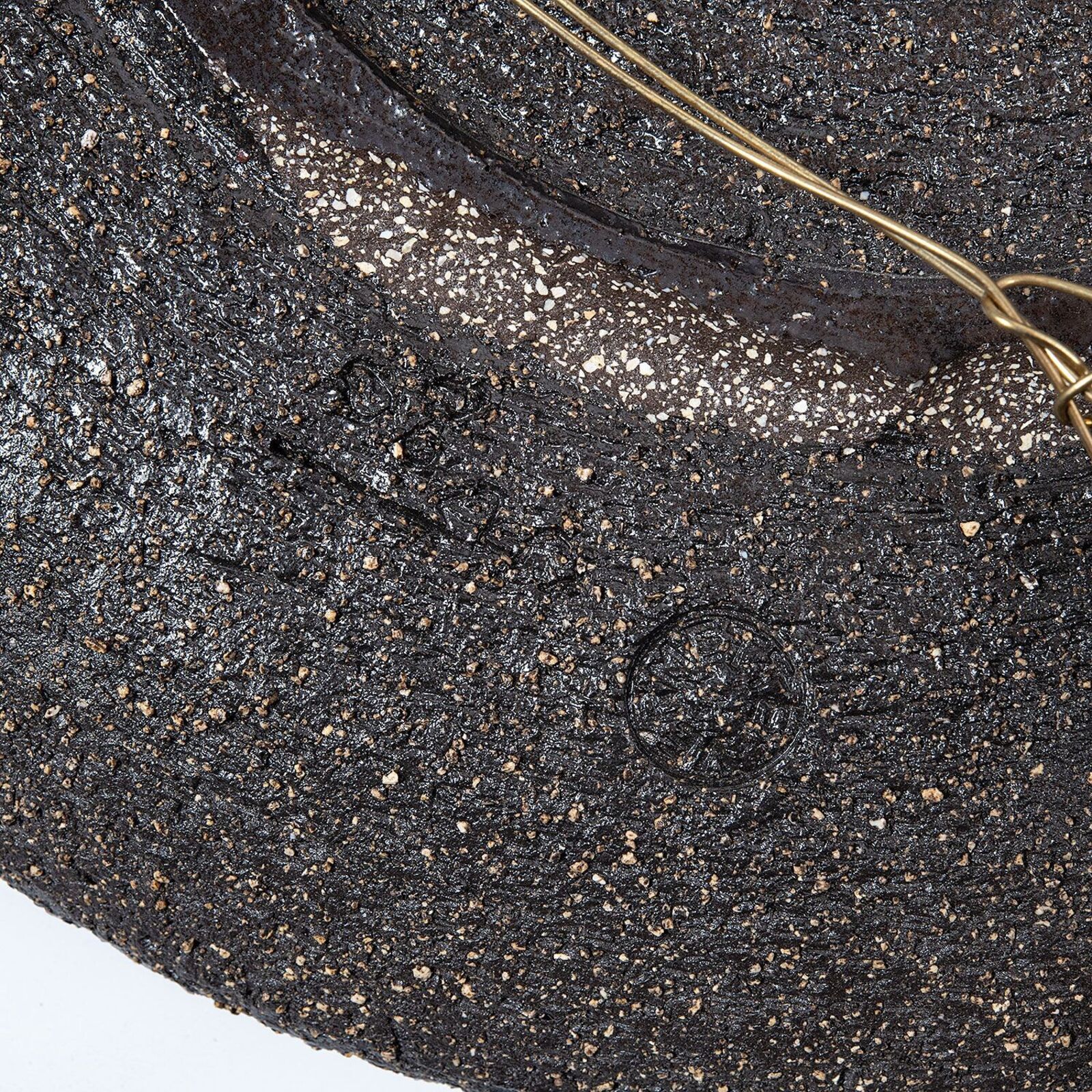A rustic ceramic plate featuring a dark textured surface with white speckles and blue glaze accents.