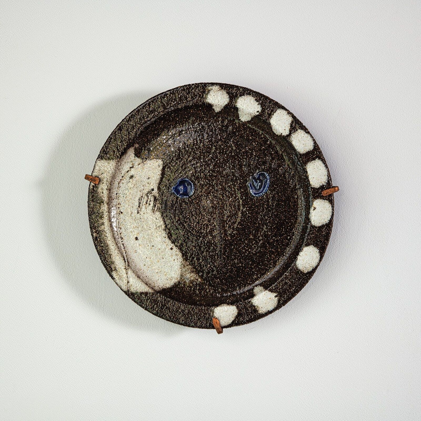 A rustic ceramic plate featuring a dark textured surface with white speckles and blue glaze accents.