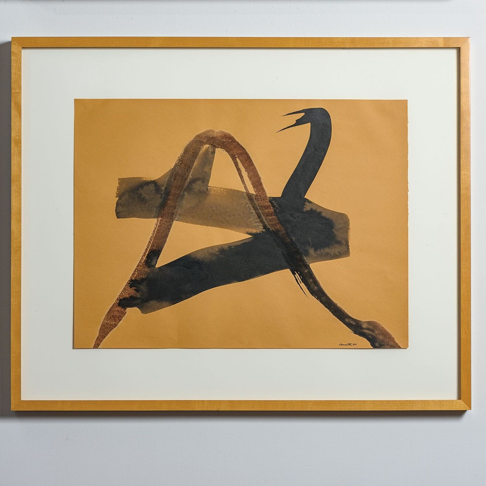 A framed abstract print featuring bold black brushstrokes on a mustard-yellow background.