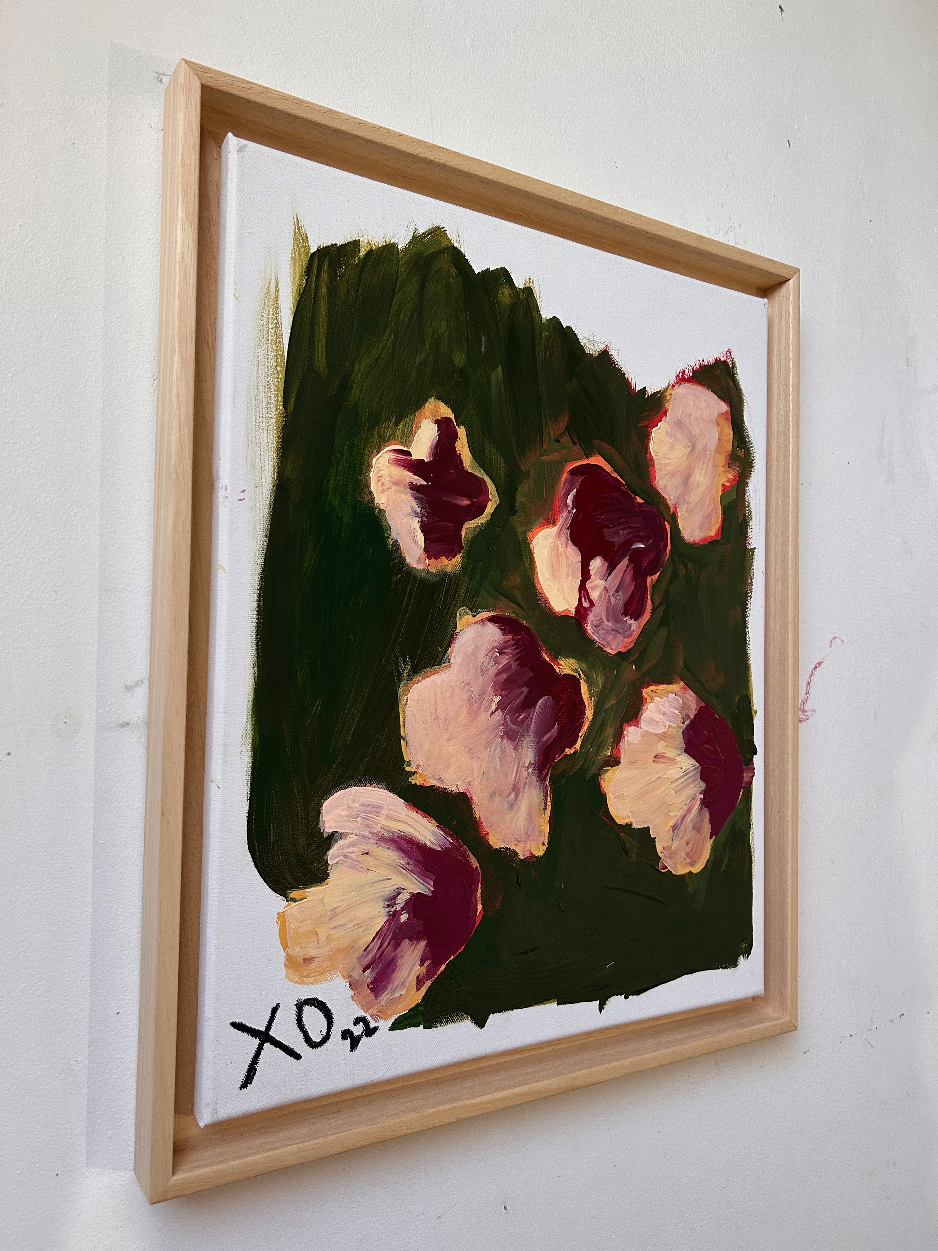A painting of flowers in a wooden frame on a wall.