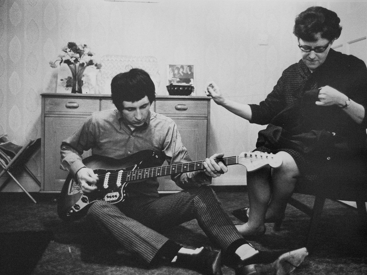 A man sitting on the floor playing a guitar next to a woman.