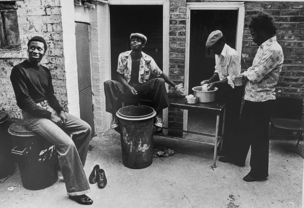 A group of men sitting around a table outside of a building.