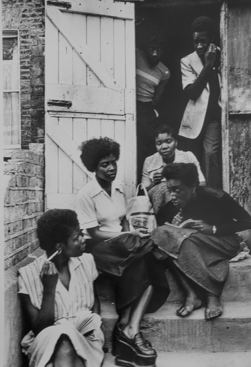A group of women sitting on the steps of a house.