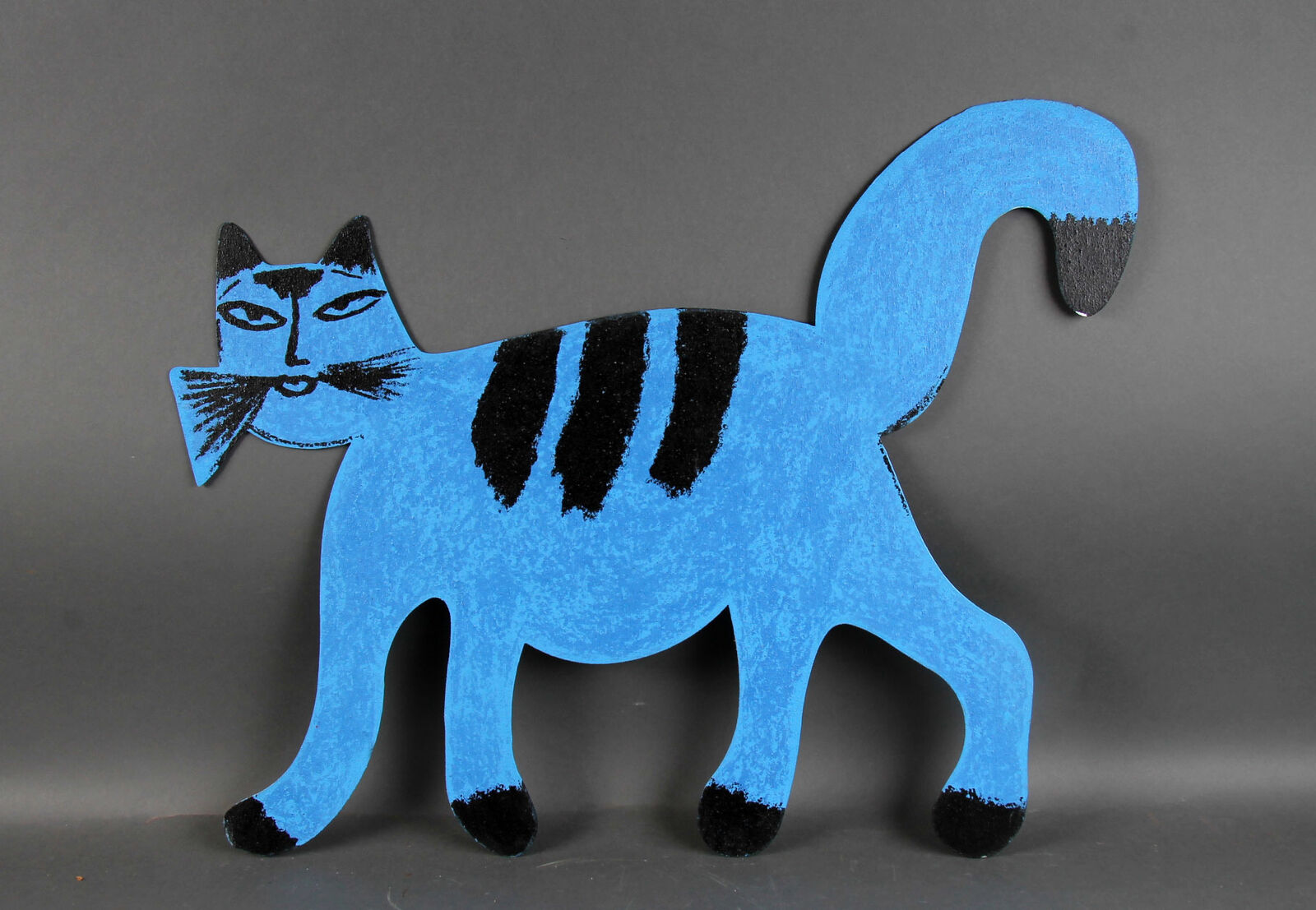 A blue cat with a black and white striped tail.