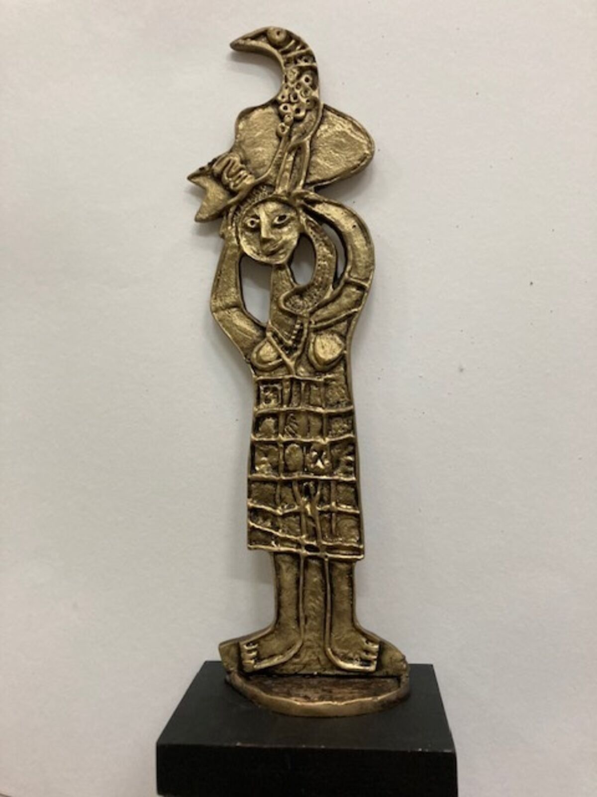 A brass statue of a woman holding a bird on her head.