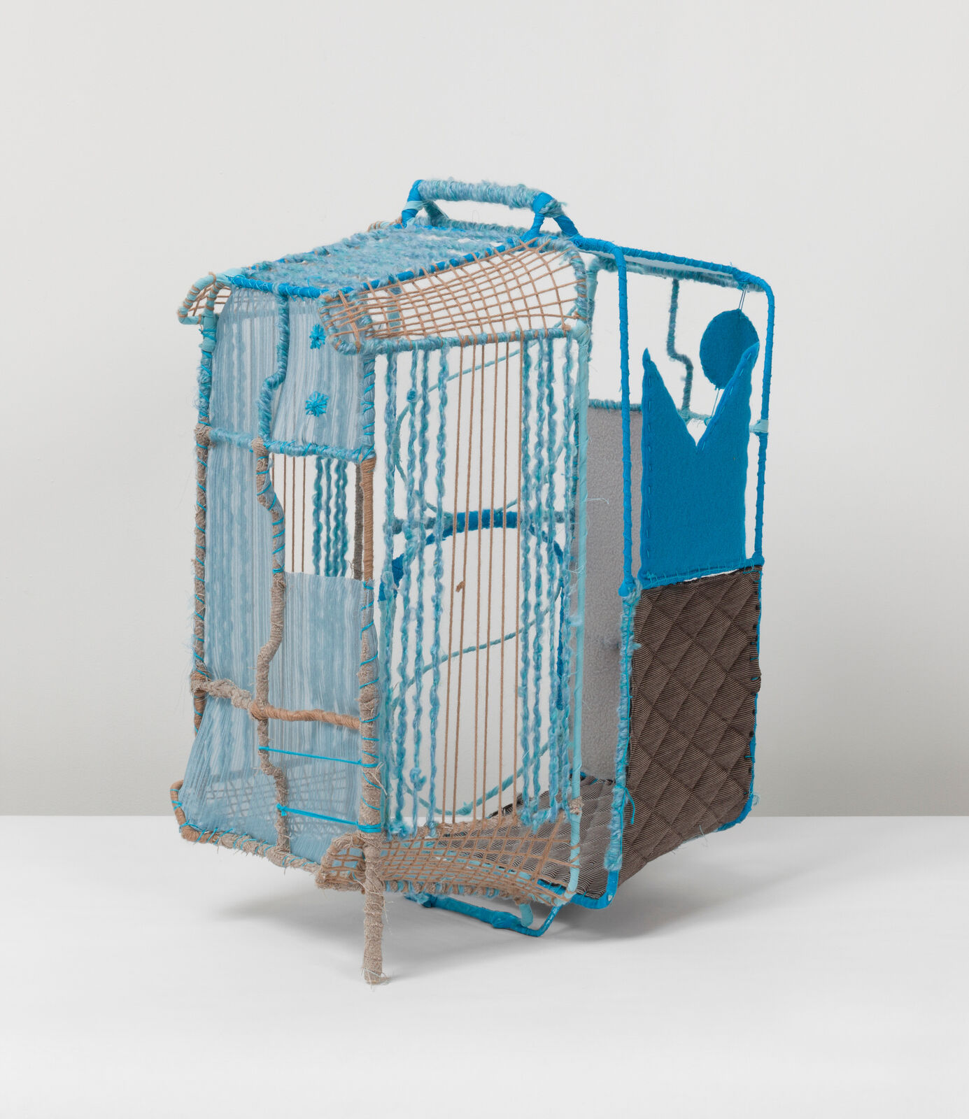 A woven, cage-like sculpture featuring blue and brown yarns with a stylized figure silhouette.
