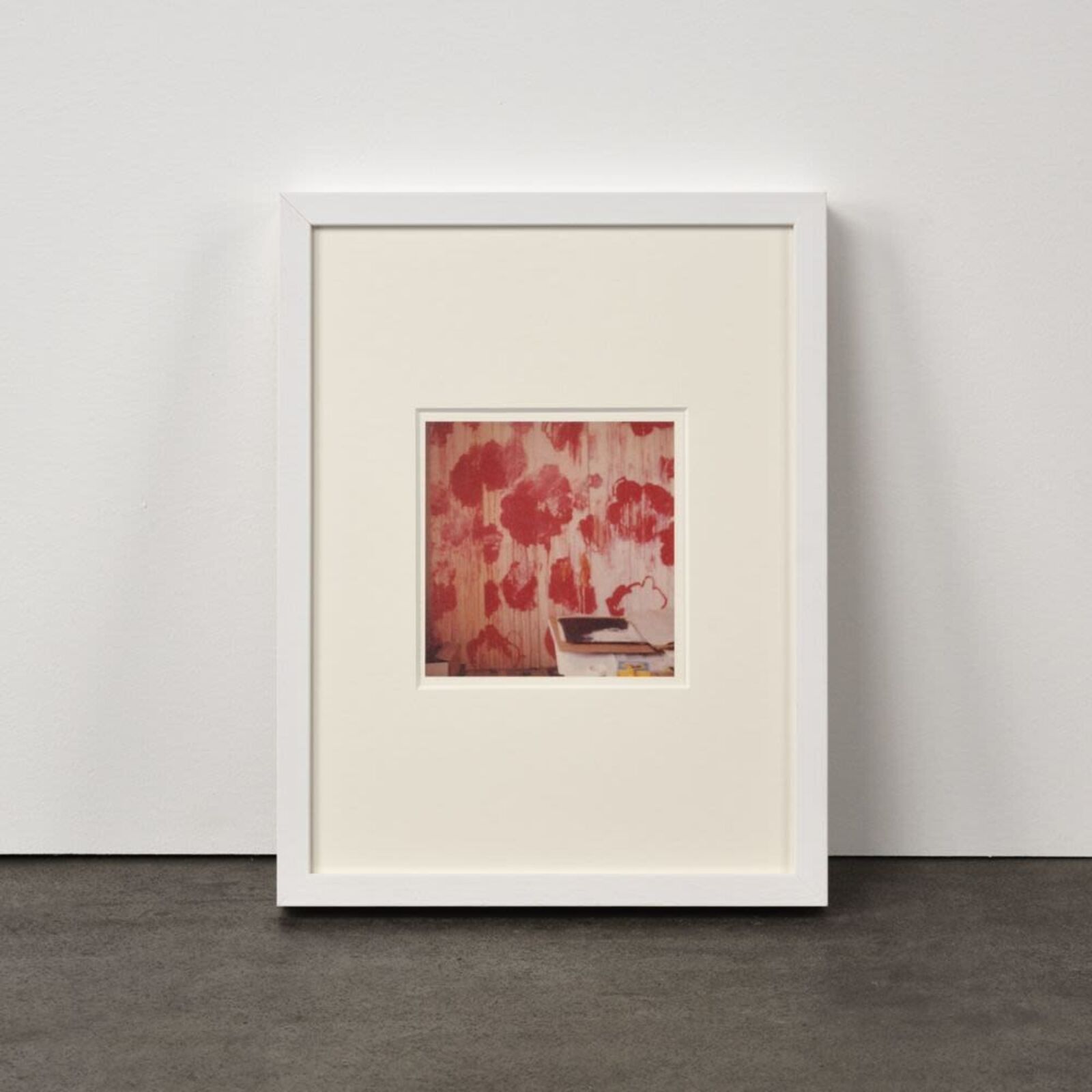 A framed photograph of a textured red floral pattern with a small book resting in the foreground.