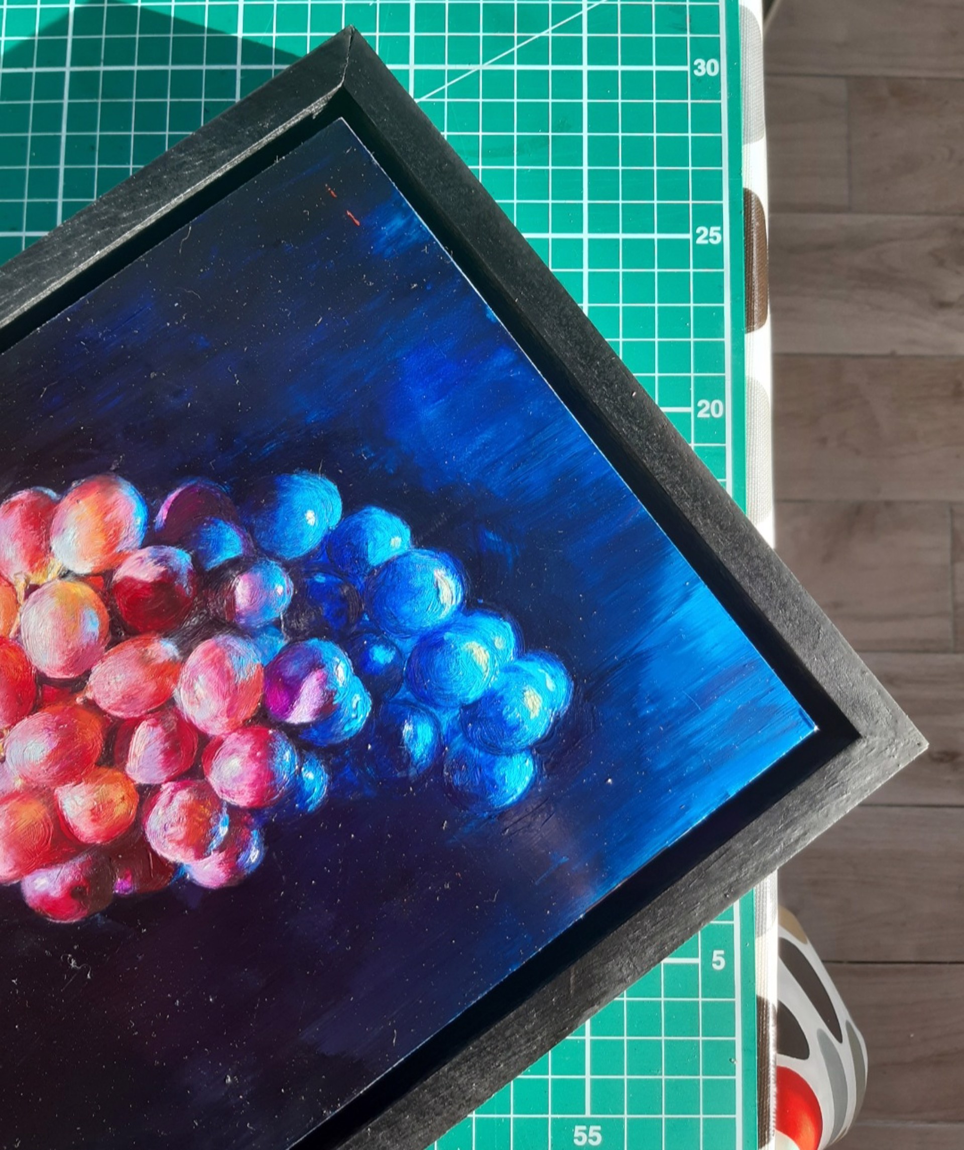 A hyper-realistic painting of a grape cluster suspended in deep shadow.