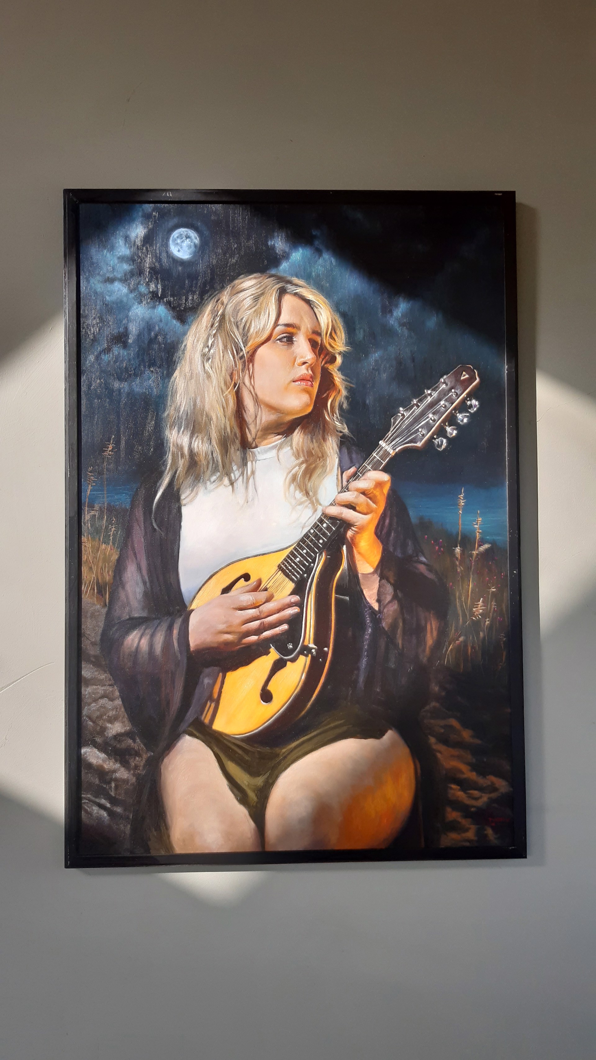 A portrait of a figure holding a mandolin against a dark, moonlit night sky.