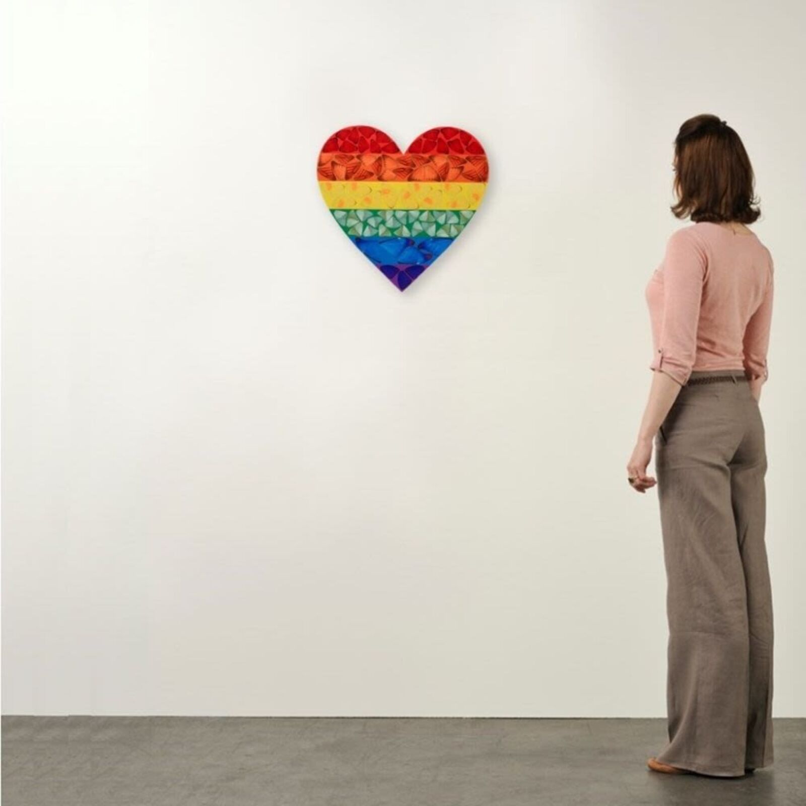 A rainbow colored heart shaped piece of art on a white background.