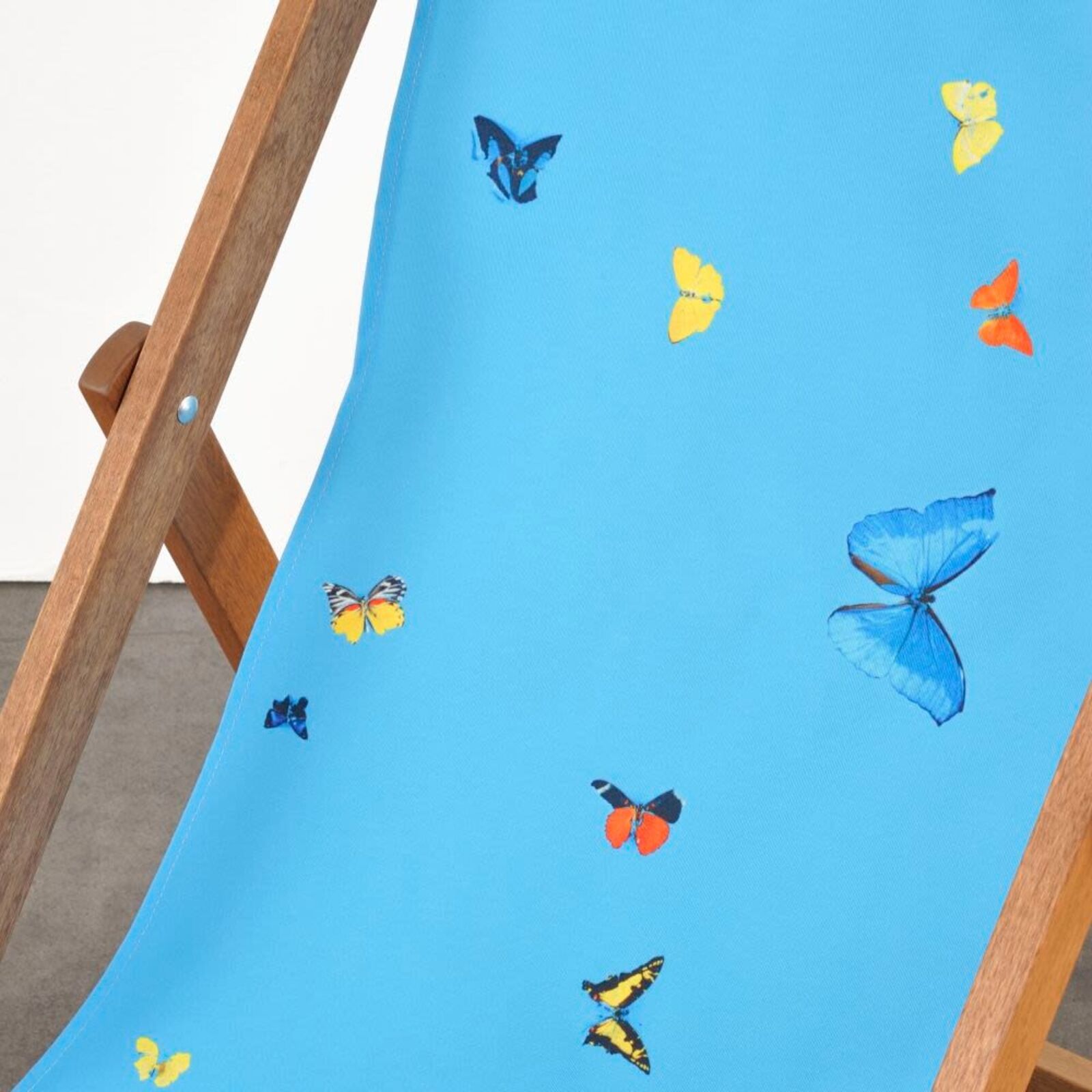 A wooden deck chair with a blue butterfly print on it.