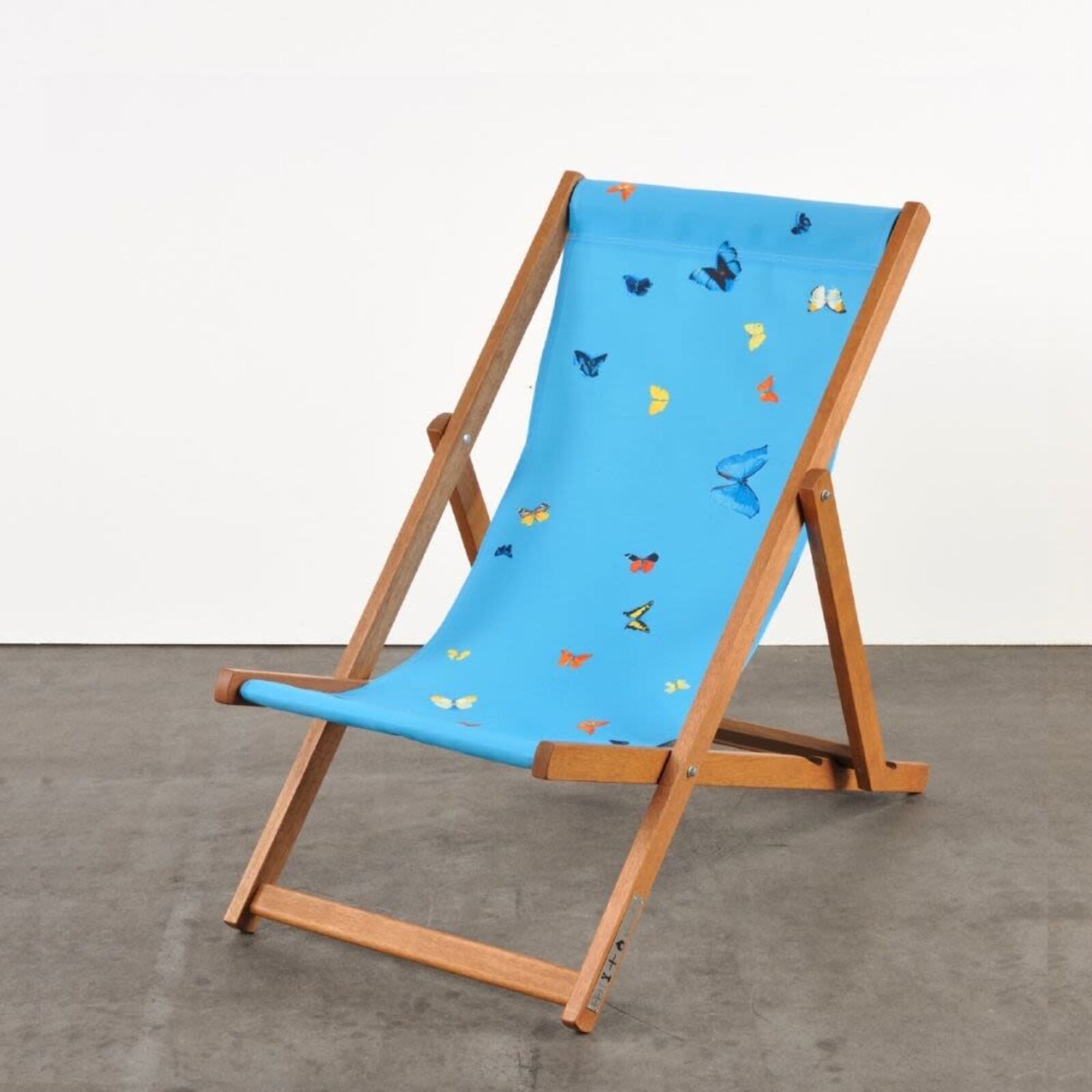 A wooden deck chair with a blue butterfly print on it.