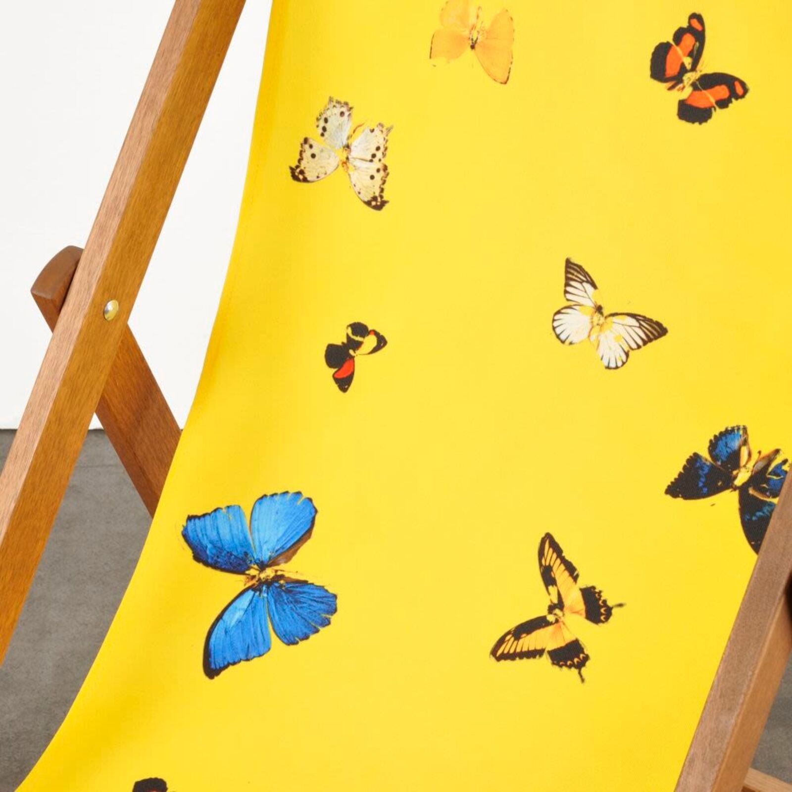 A yellow deck chair with butterflies on it.