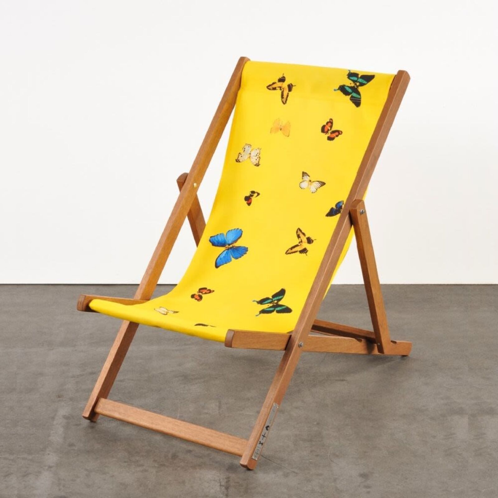 A yellow deck chair with butterflies on it.