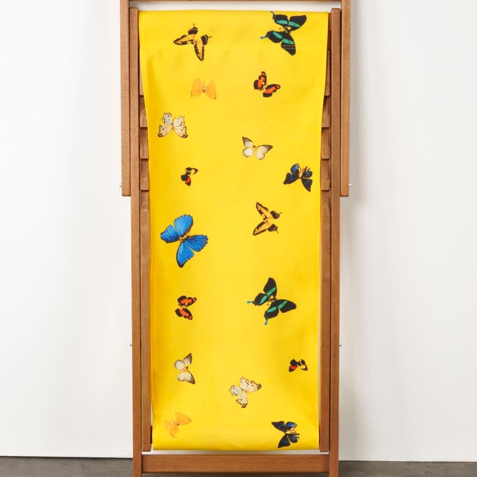 A yellow deck chair with butterflies on it.