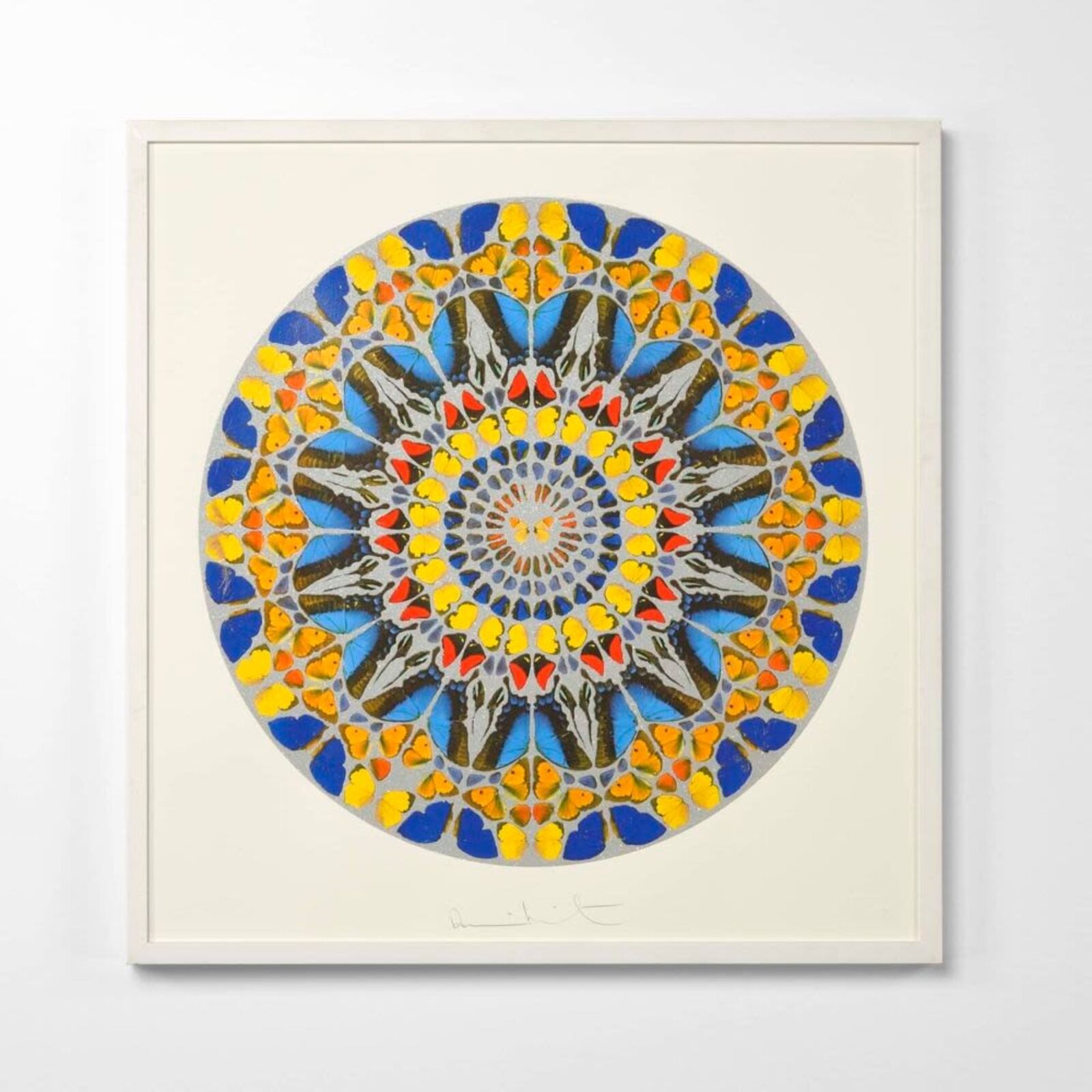 A blue and yellow mandala on a white wall in a room.