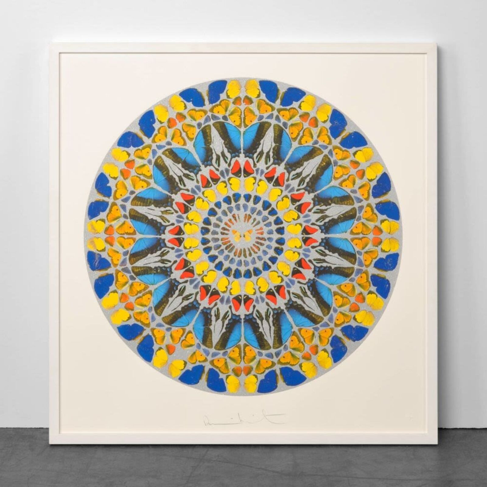 A blue and yellow mandala on a white wall in a room.