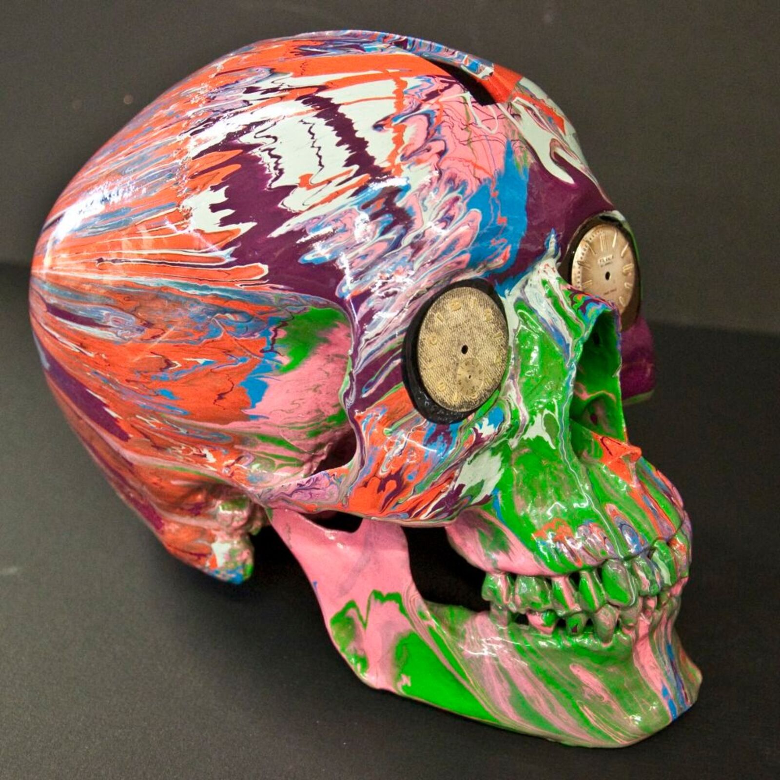 A colorful skull with a clock on top of it.