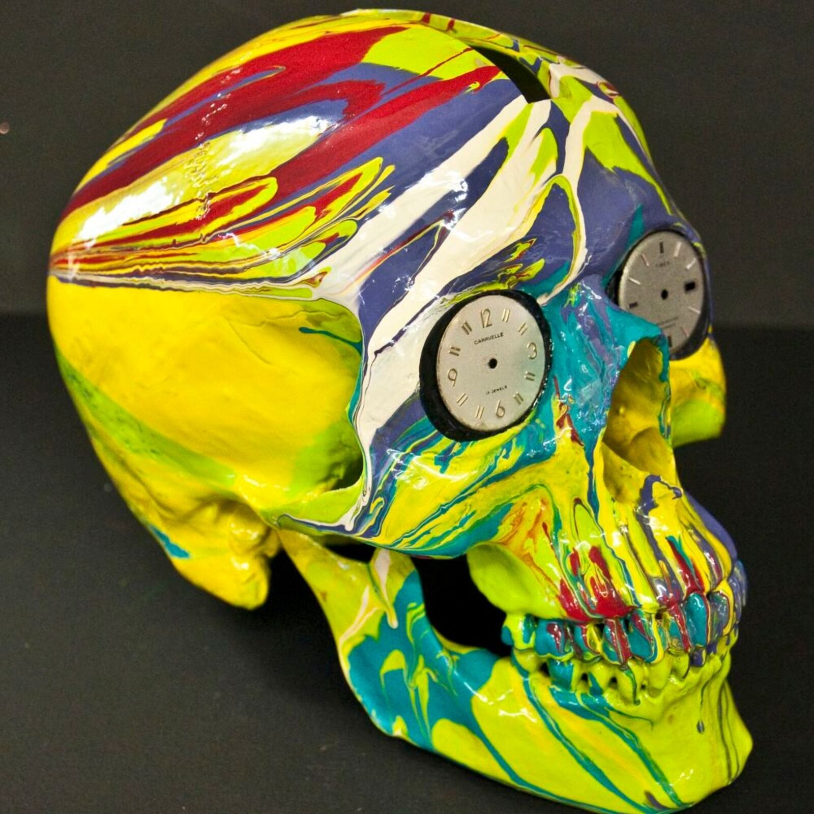 A colorful skull with a clock on top of it.