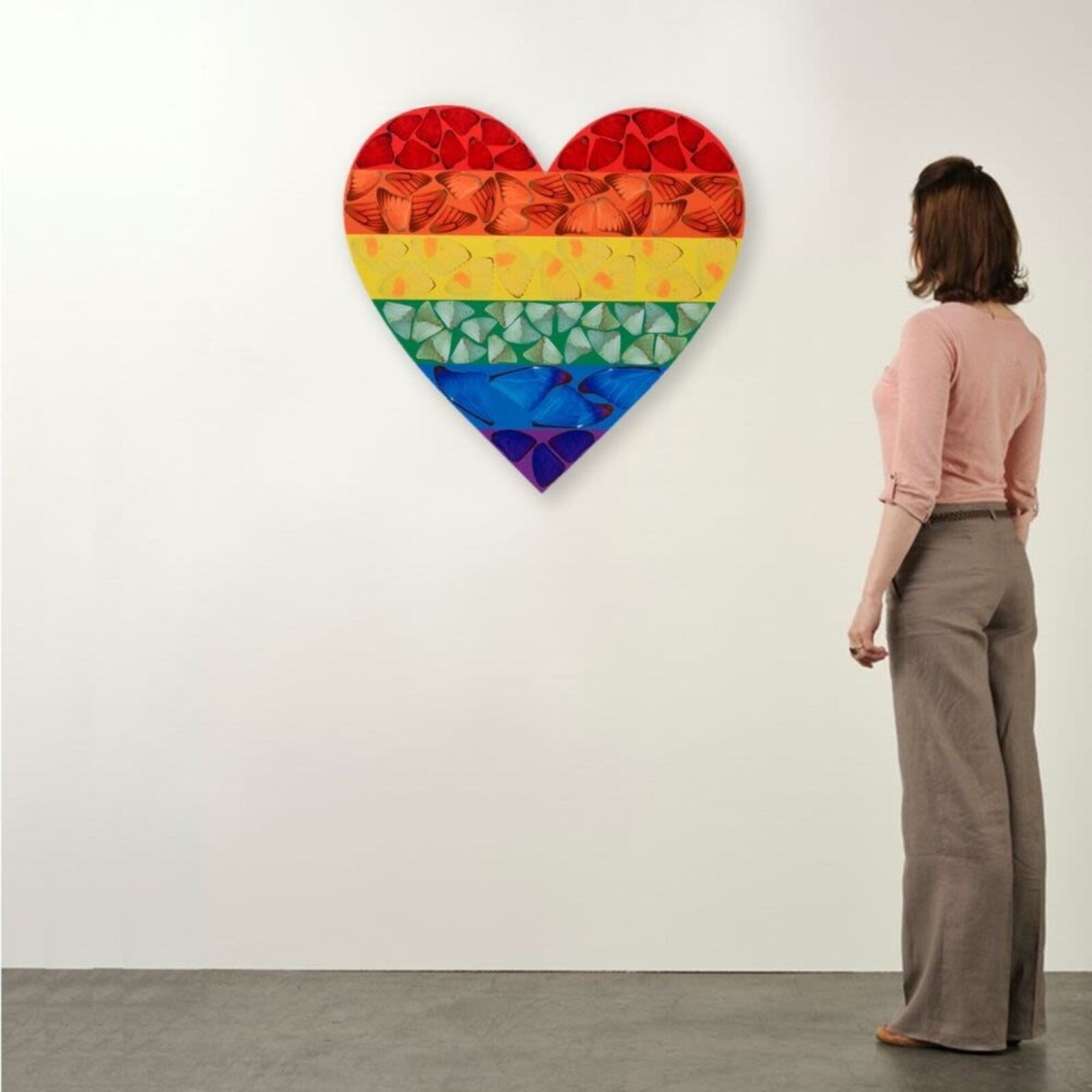 A rainbow colored heart shaped piece of art on a white background.