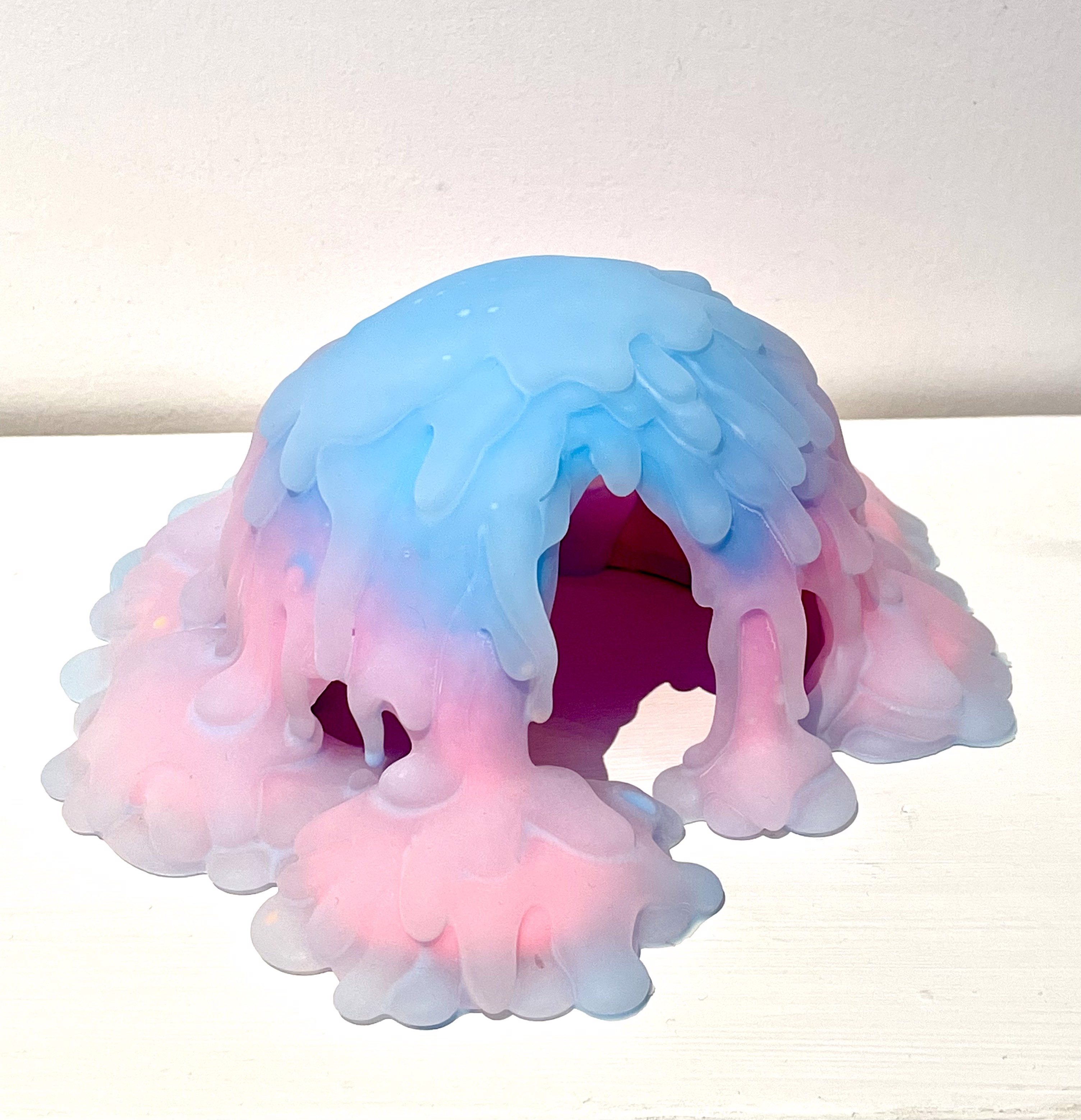 A pink and blue jellyfish shaped object on a white surface.