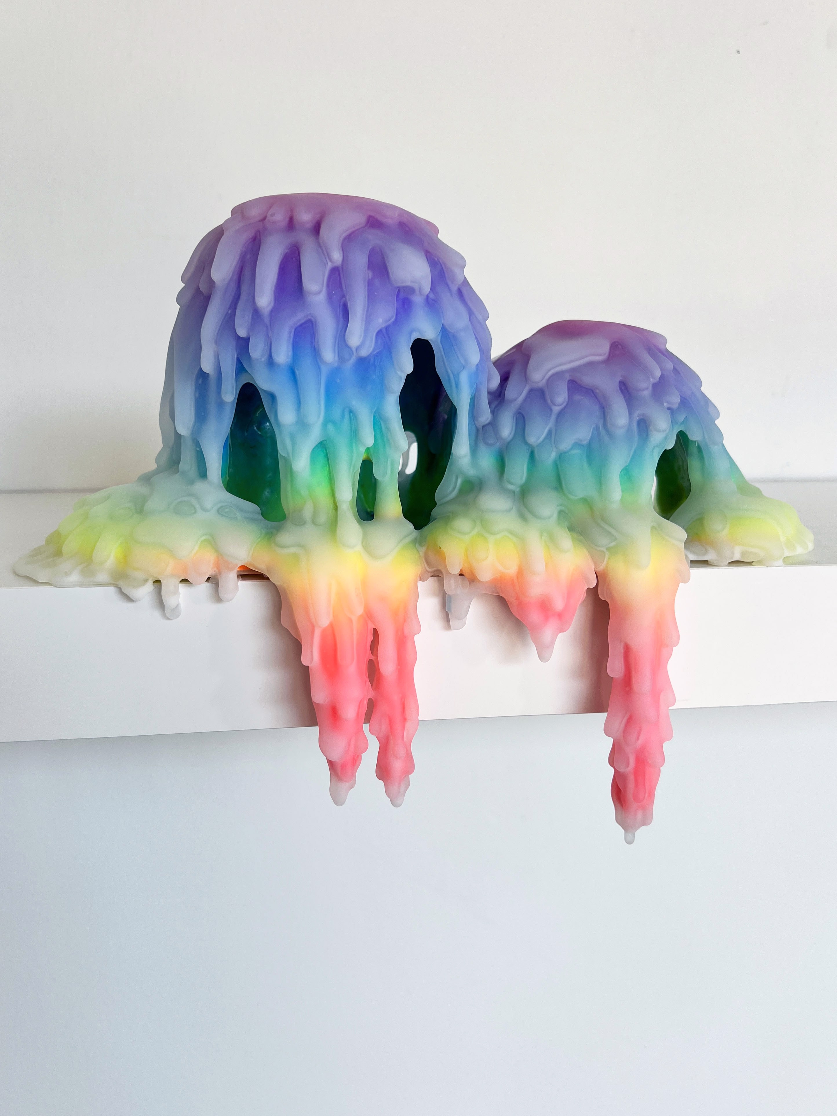 A pair of colorful jellyfish sitting on top of a white shelf.