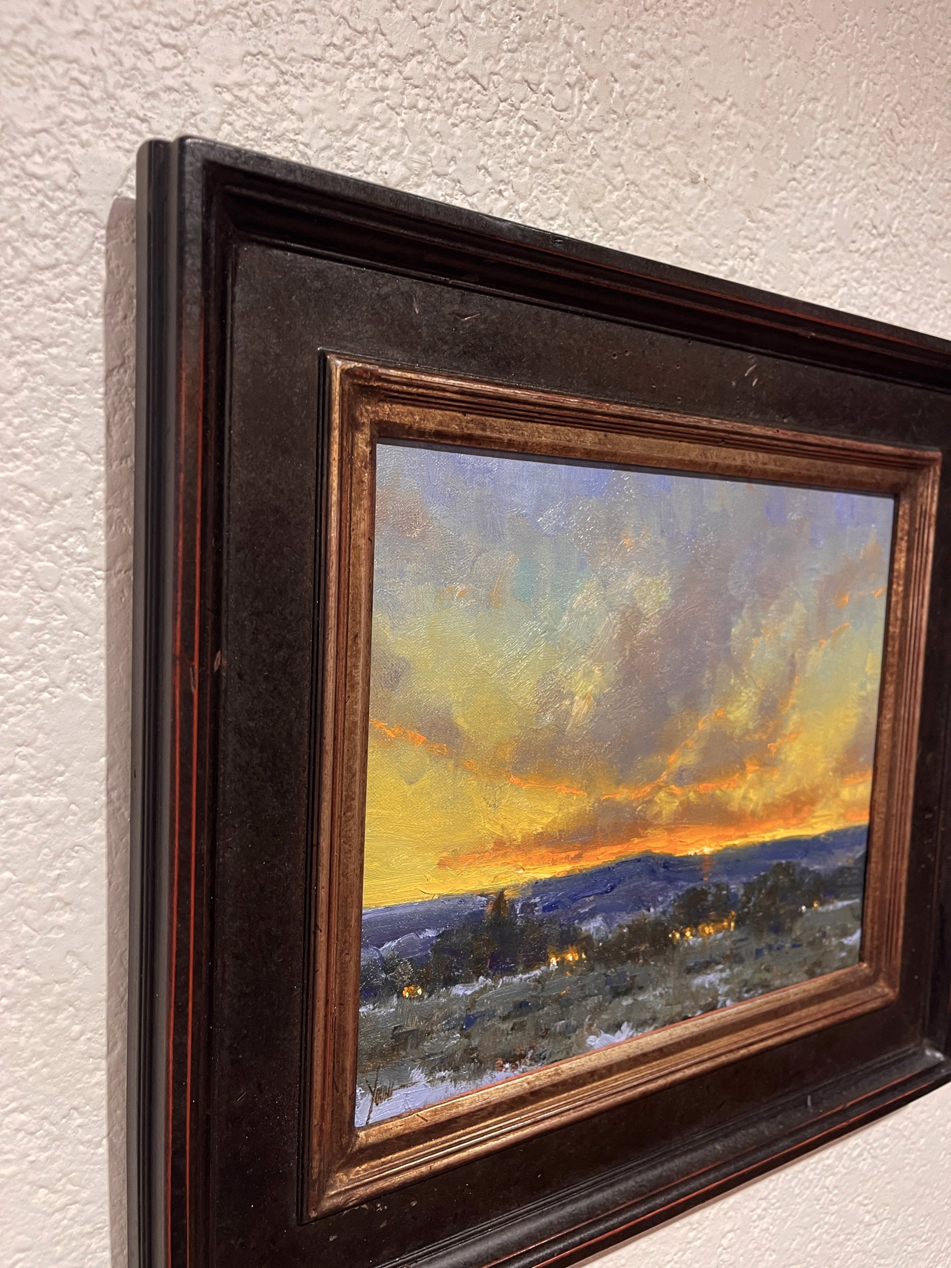 A dramatic landscape painting capturing a twilight sky over a dark, snowy foreground.