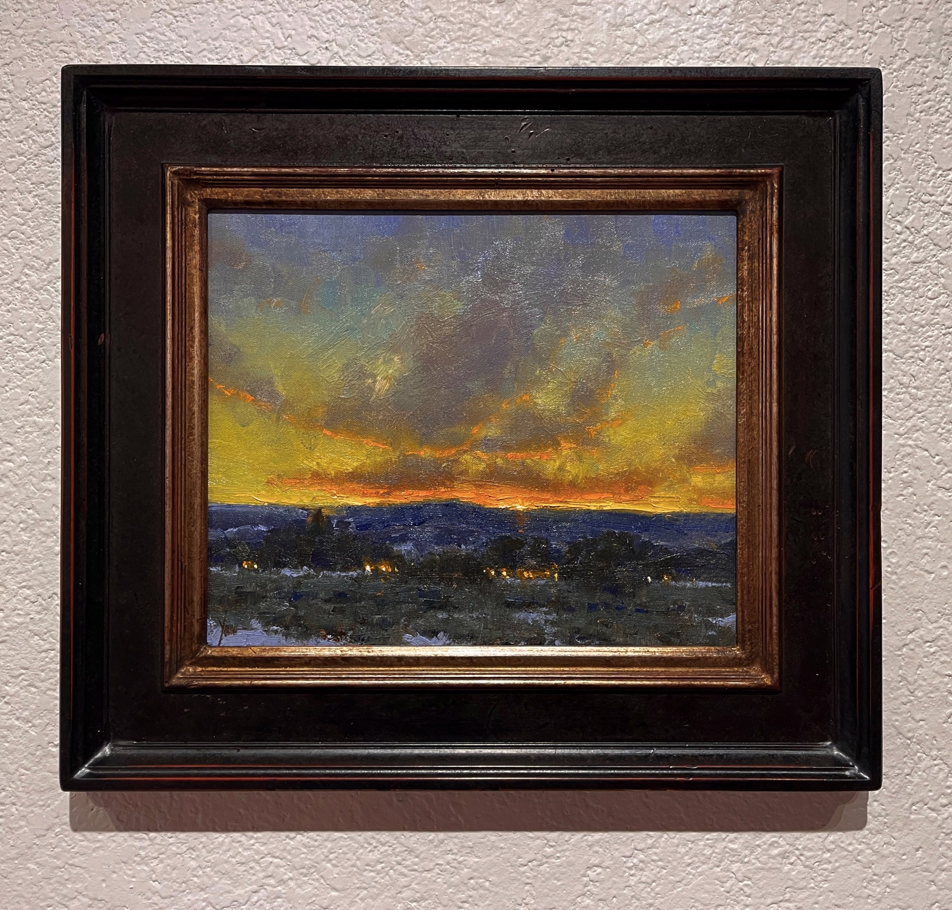 A dramatic landscape painting capturing a twilight sky over a dark, snowy foreground.