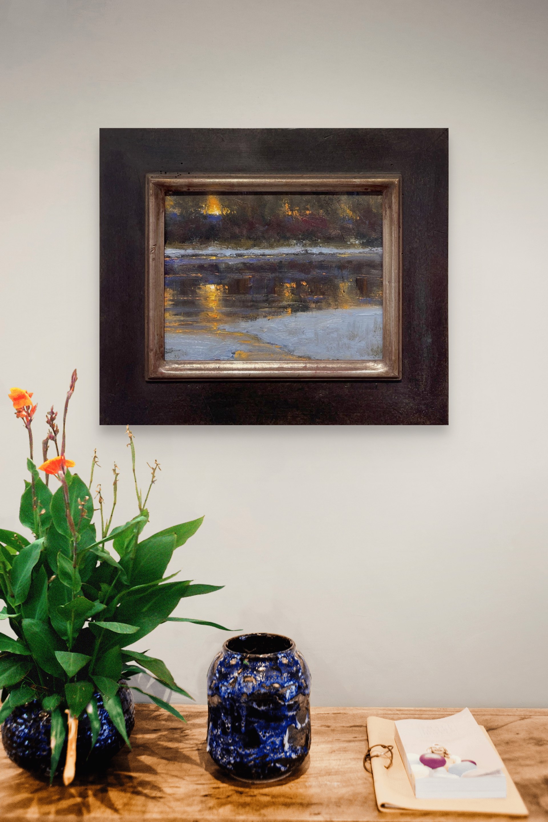 A nocturnal landscape painting capturing the shimmering reflections of warm lights on a dark, textured surface.