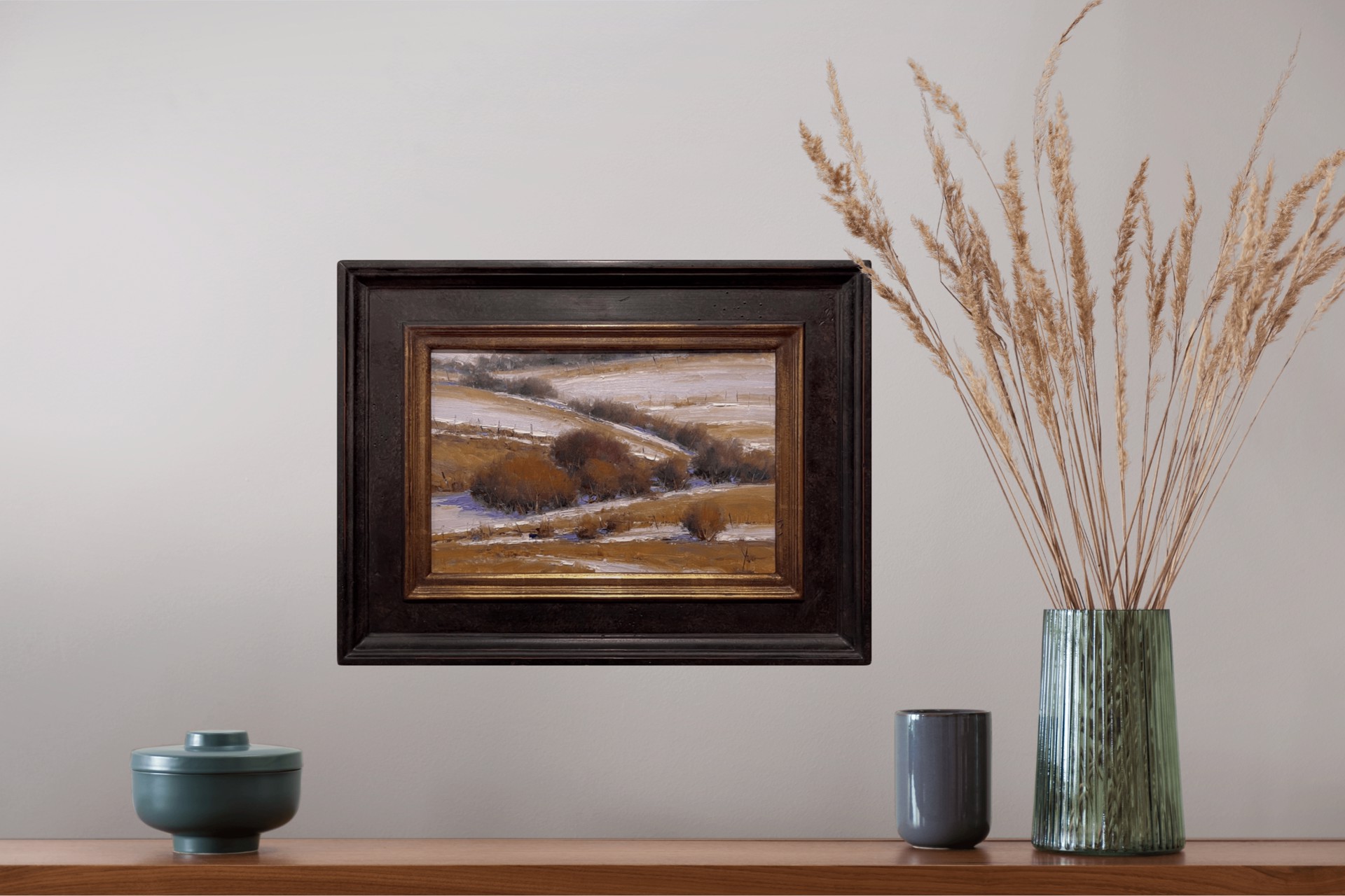 A winter landscape painting featuring snow-covered hills and dark shrubs.