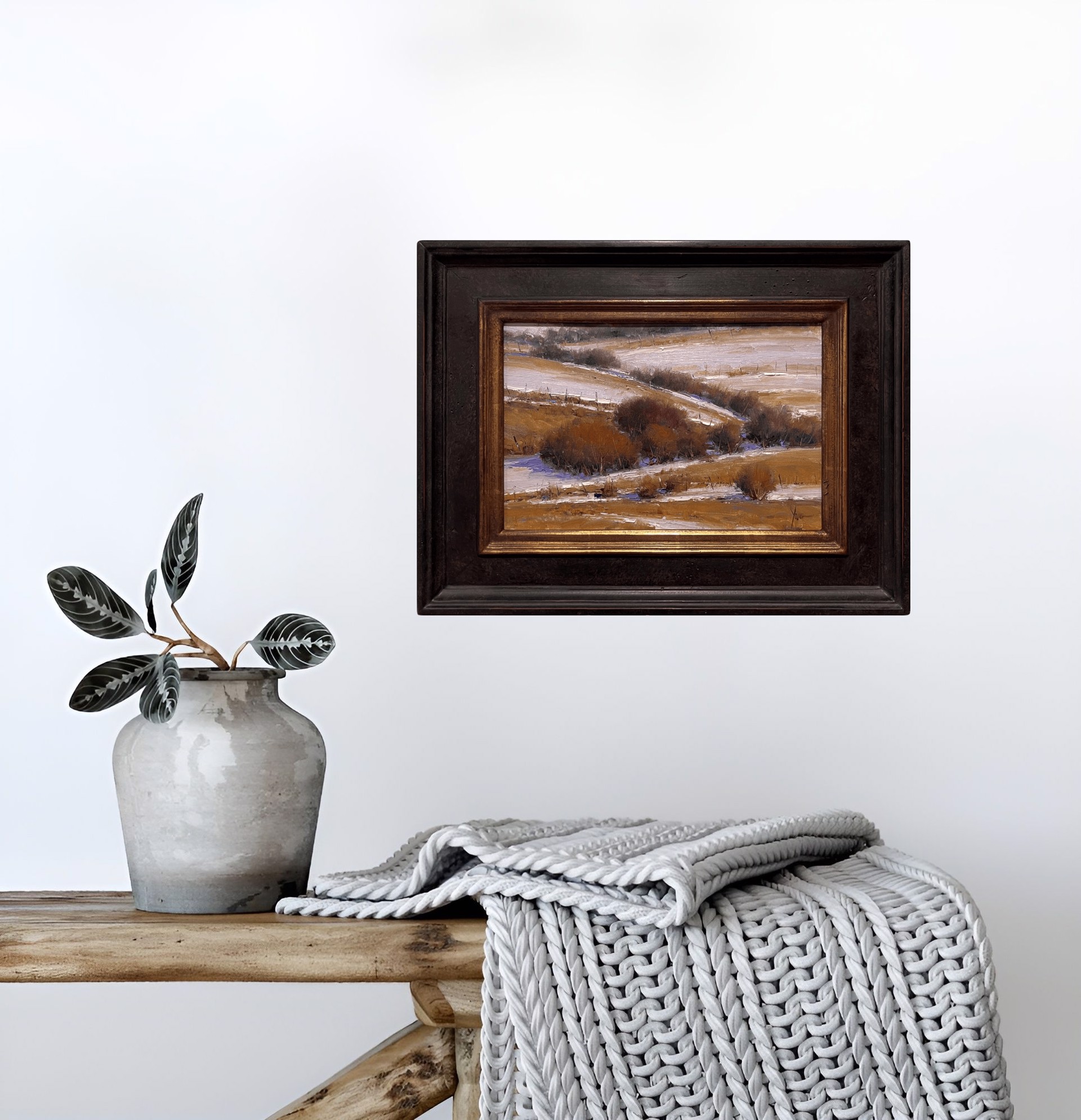 A winter landscape painting featuring snow-covered hills and dark shrubs.