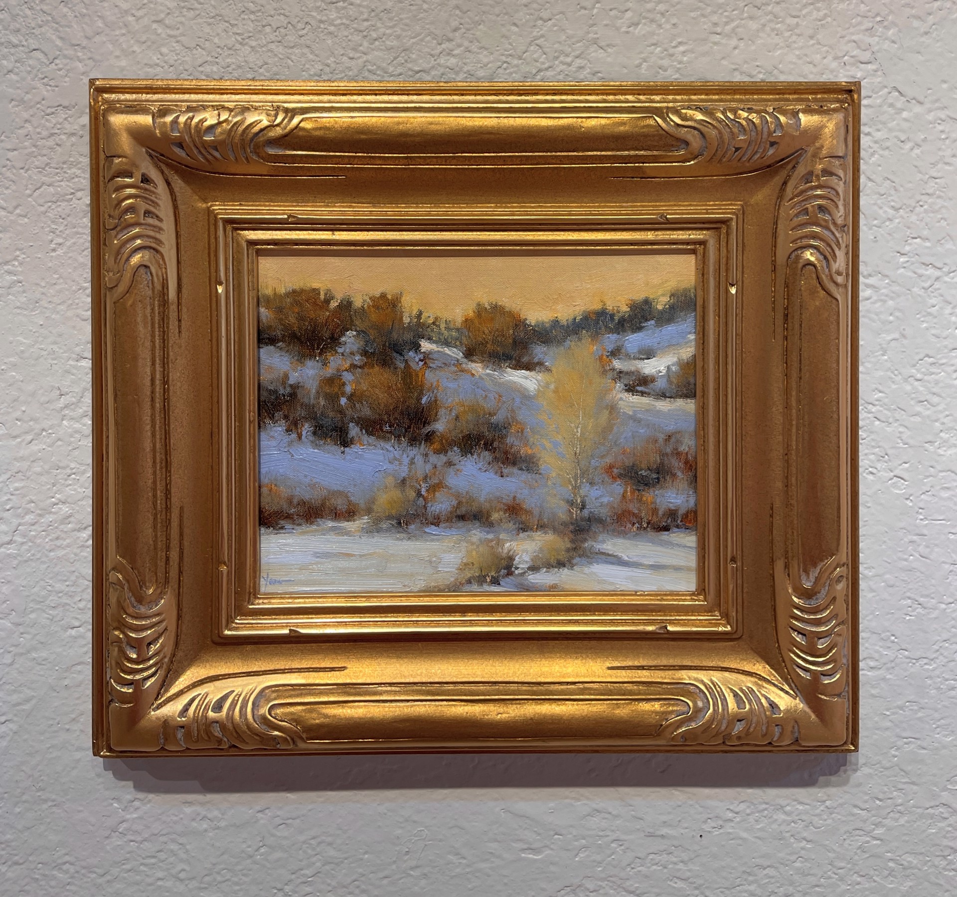 A winter landscape painting capturing a snowy hillside under a warm, golden sky.