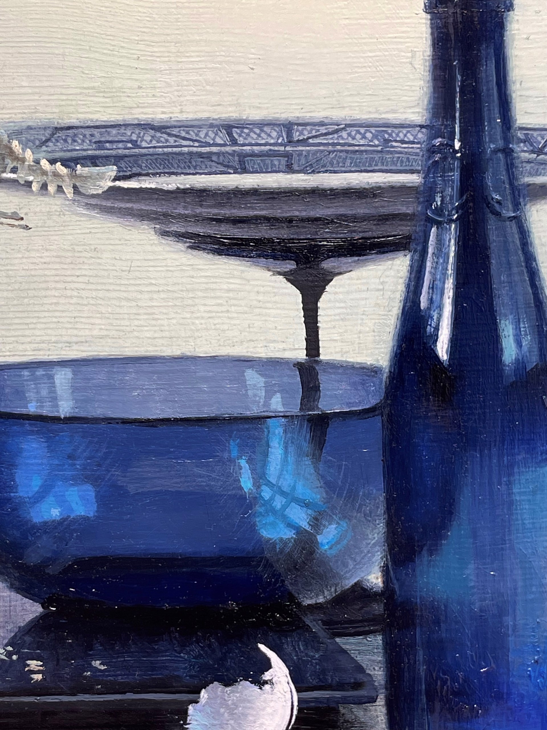 A surreal still life featuring a bird skeleton, blue glassware, and a bottle on a table.