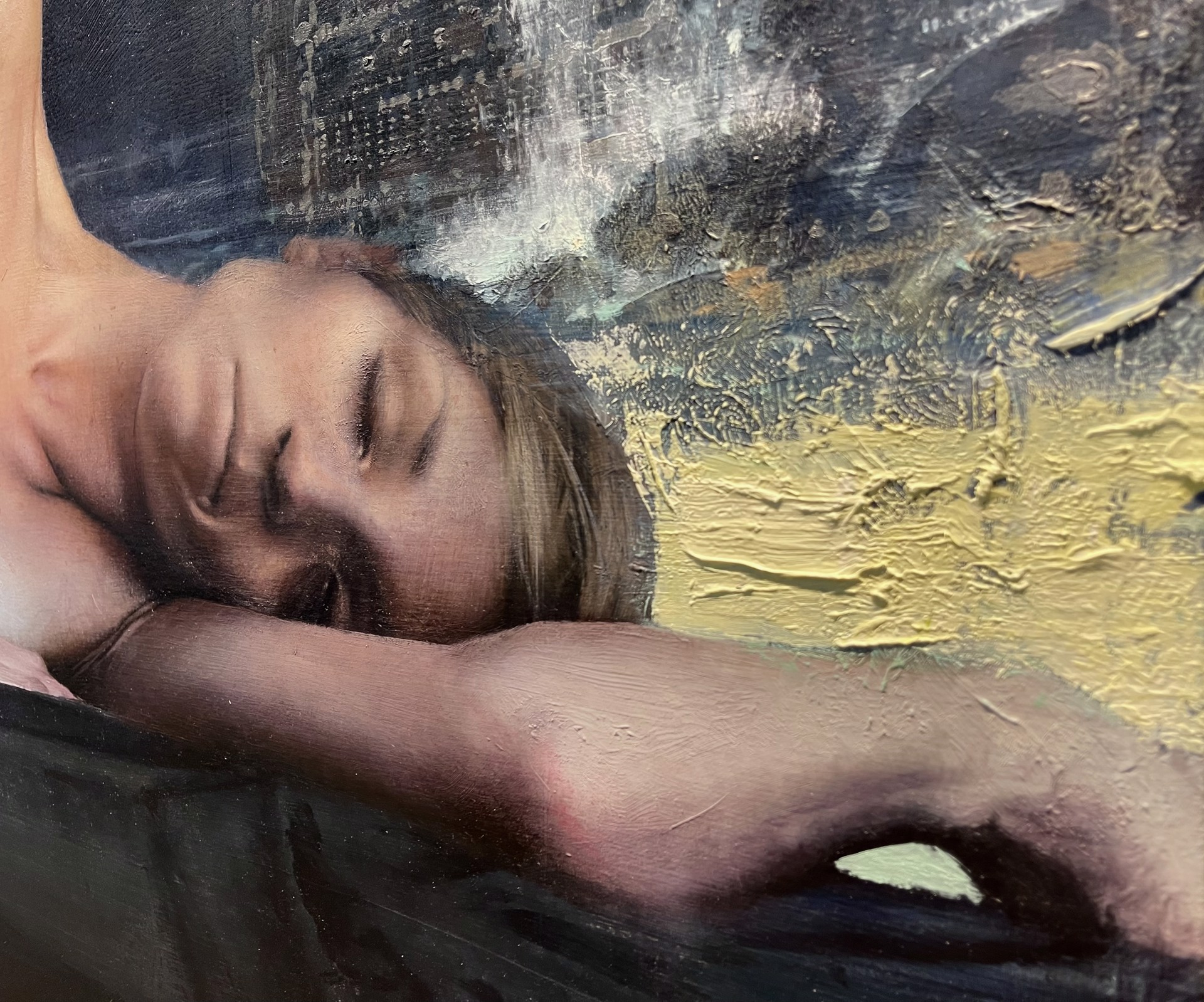 A nude figure lies on a dark surface in a dimly lit, atmospheric scene.
