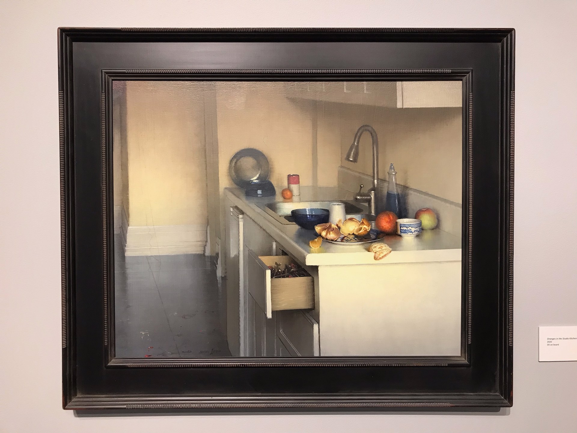 A quiet kitchen scene featuring a cluttered countertop with fruit, dishes, and an open drawer.