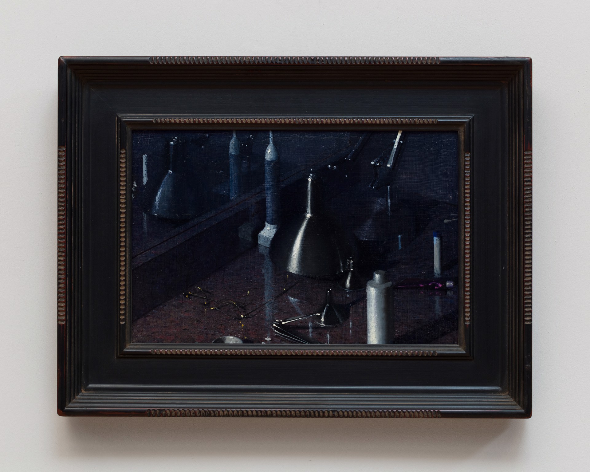 A dark, moody still life featuring metallic funnels and paint tubes on a reflective surface.