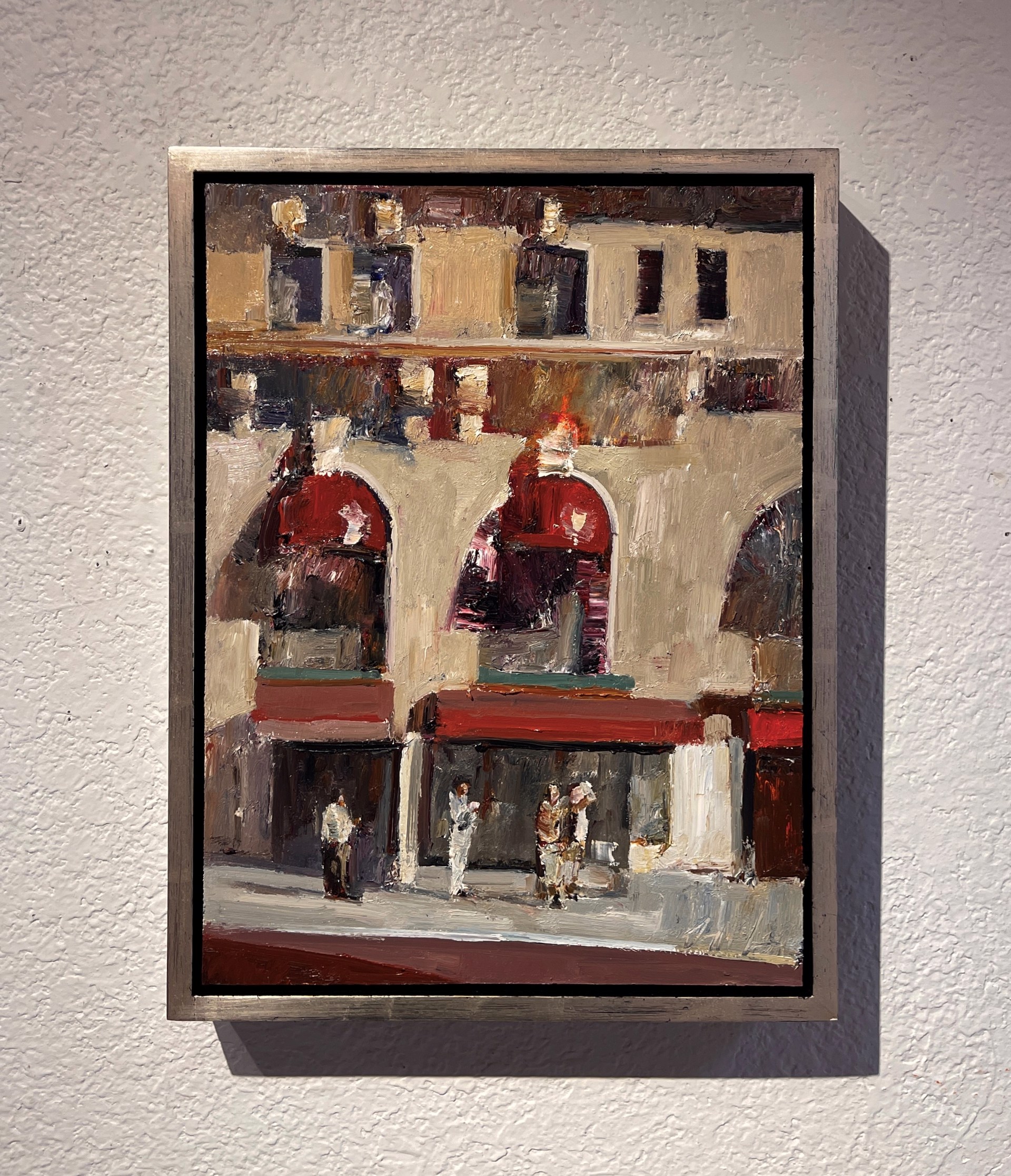 An expressive painting of a sunlit plaza with arched storefronts and figures gathered below.