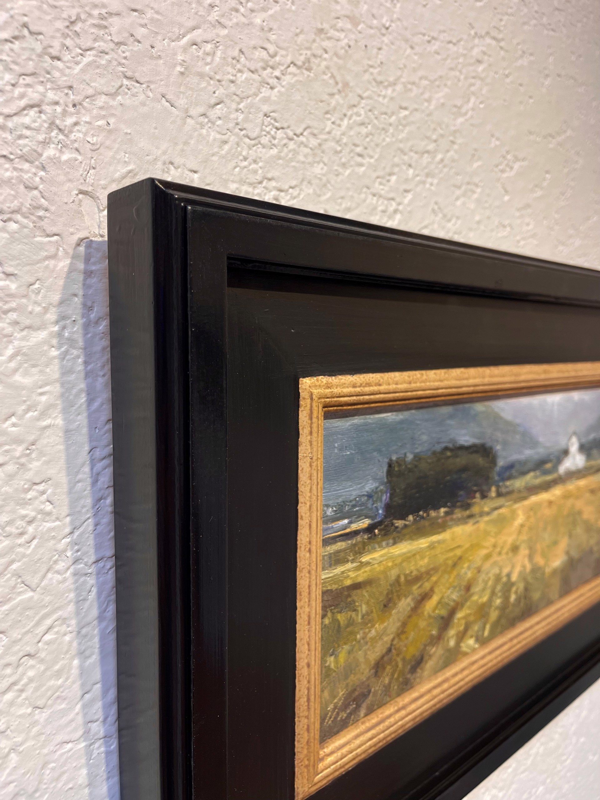 A painting of a field with a church in the distance.