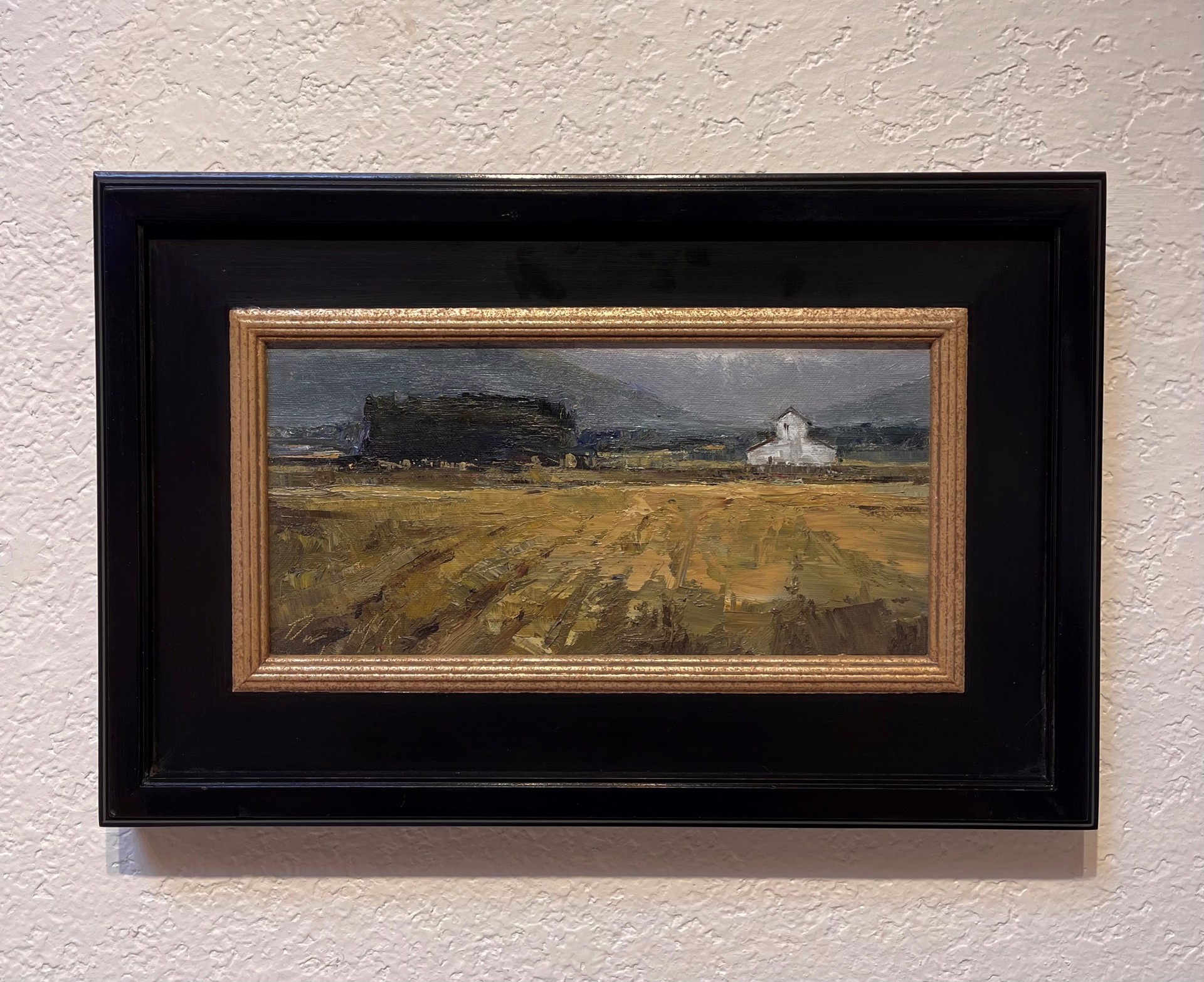 A painting of a field with a church in the distance.