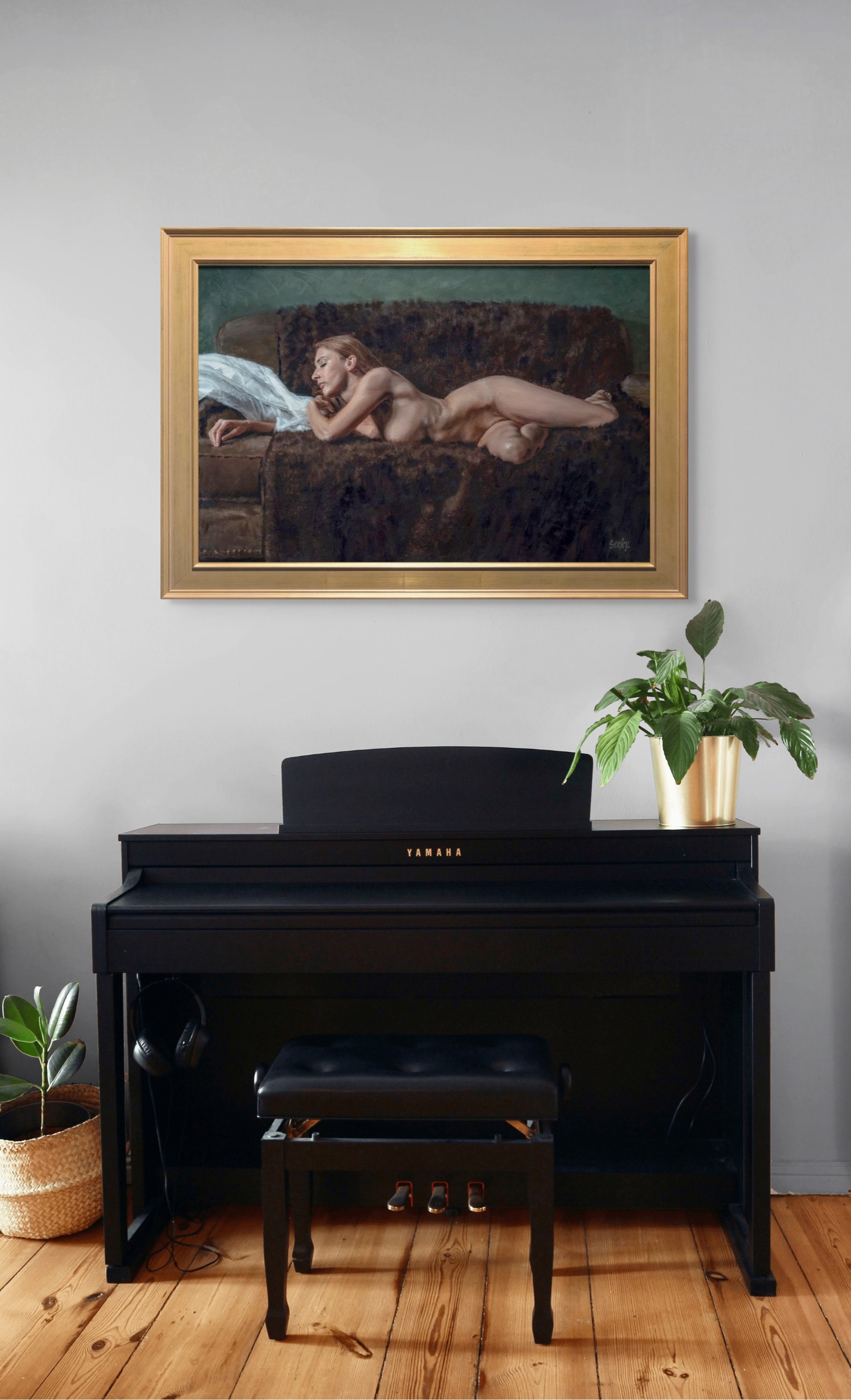 A nude figure rests on a dark sofa with a white sheet nearby.