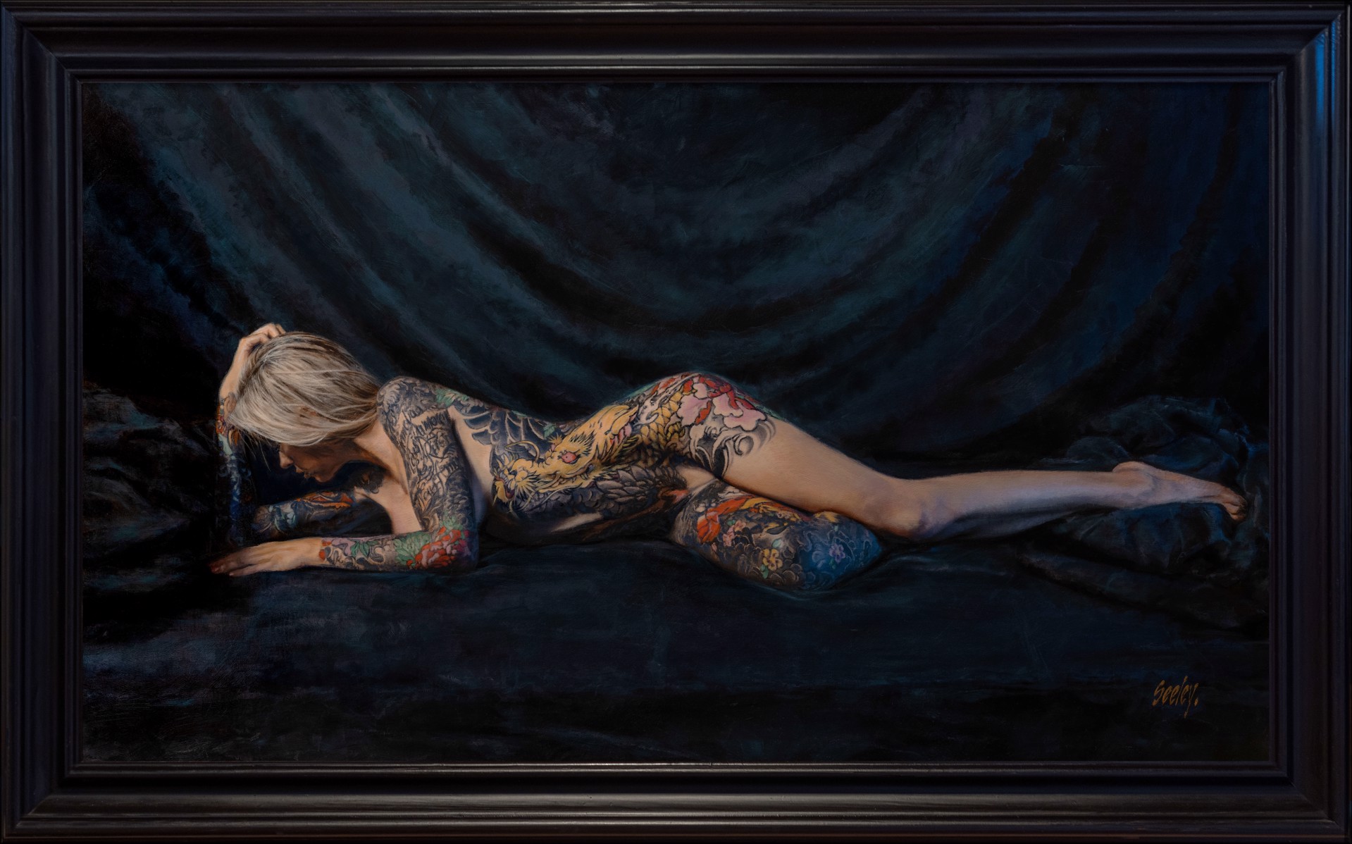 A figure with extensive colorful tattoos lies prone on a dark surface.