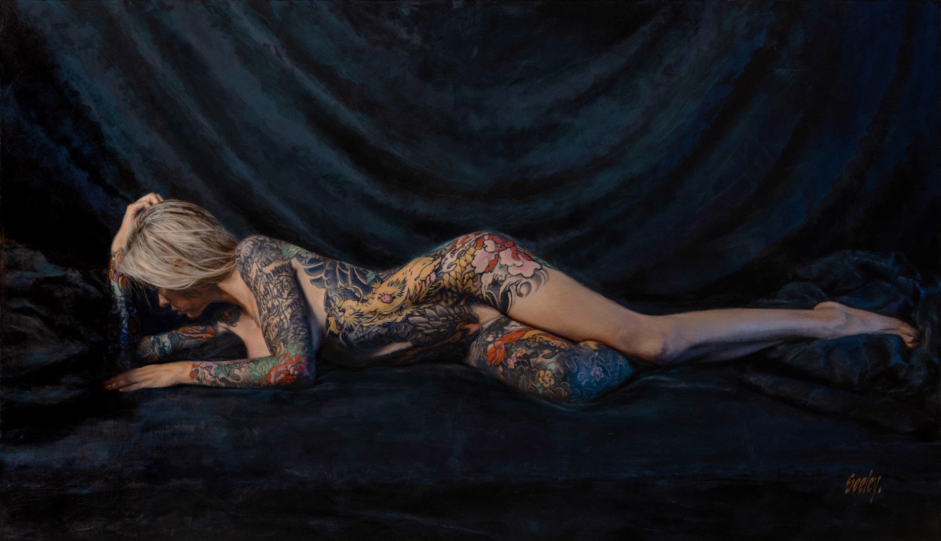 A figure with extensive colorful tattoos lies prone on a dark surface.