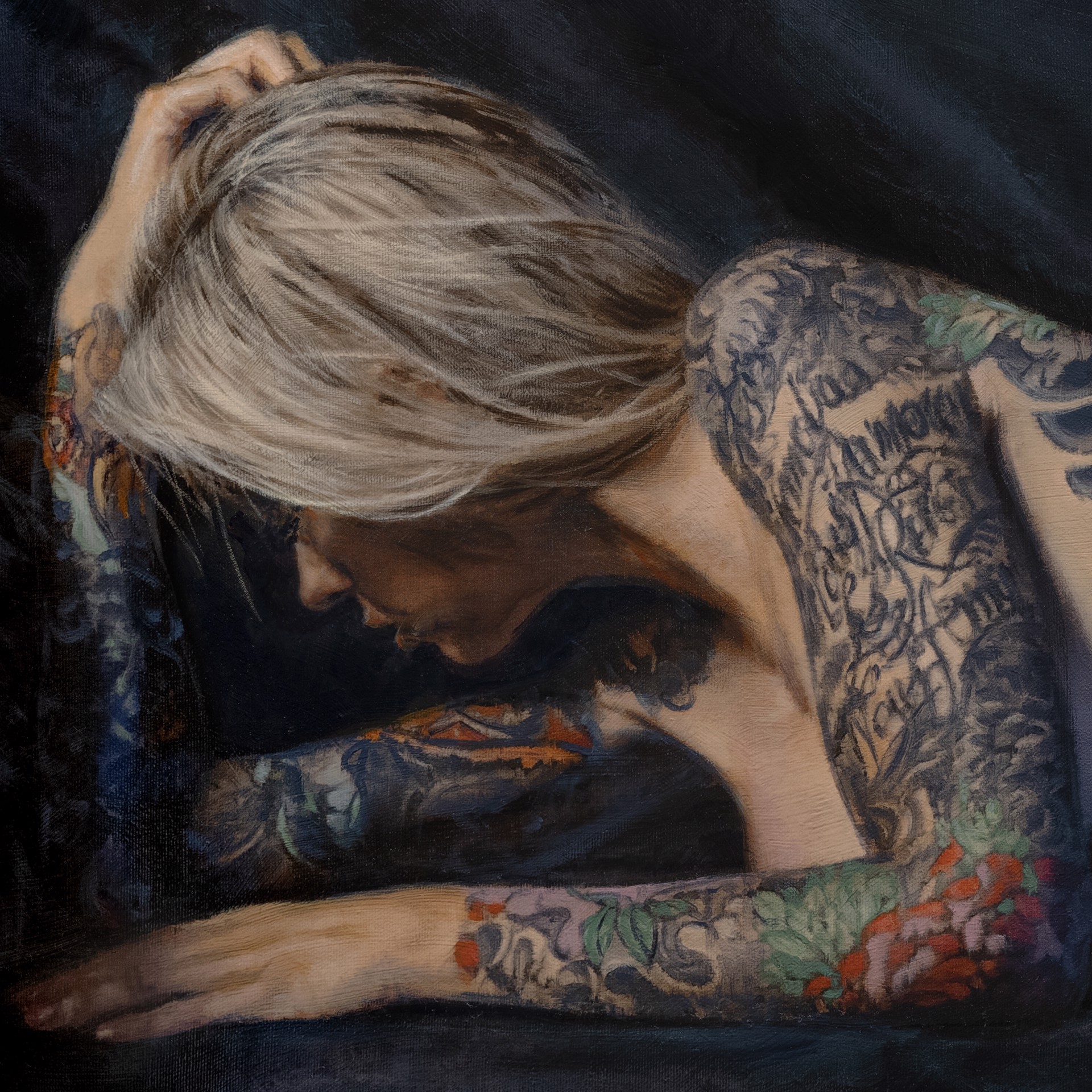 A figure with extensive colorful tattoos lies prone on a dark surface.