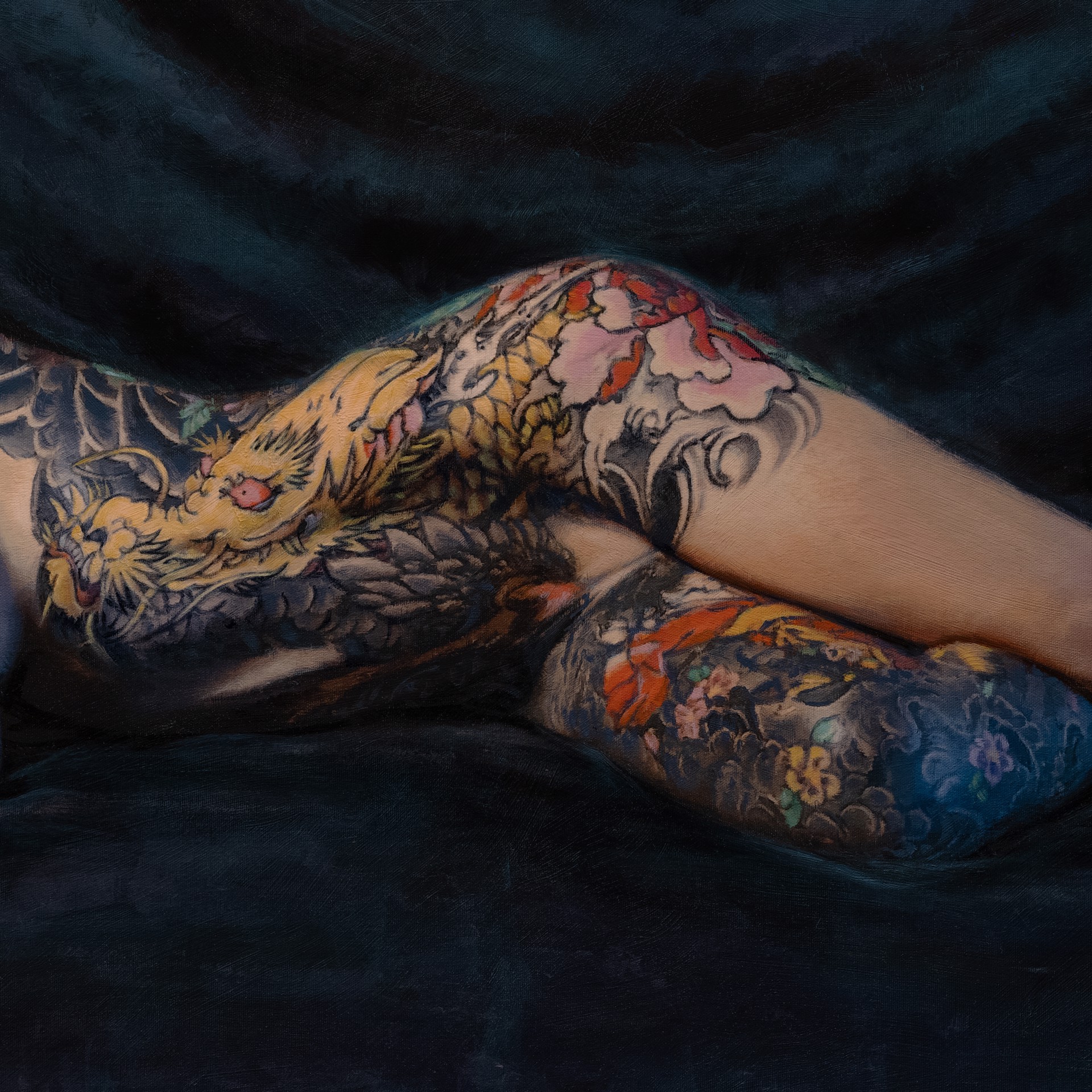 A figure with extensive colorful tattoos lies prone on a dark surface.